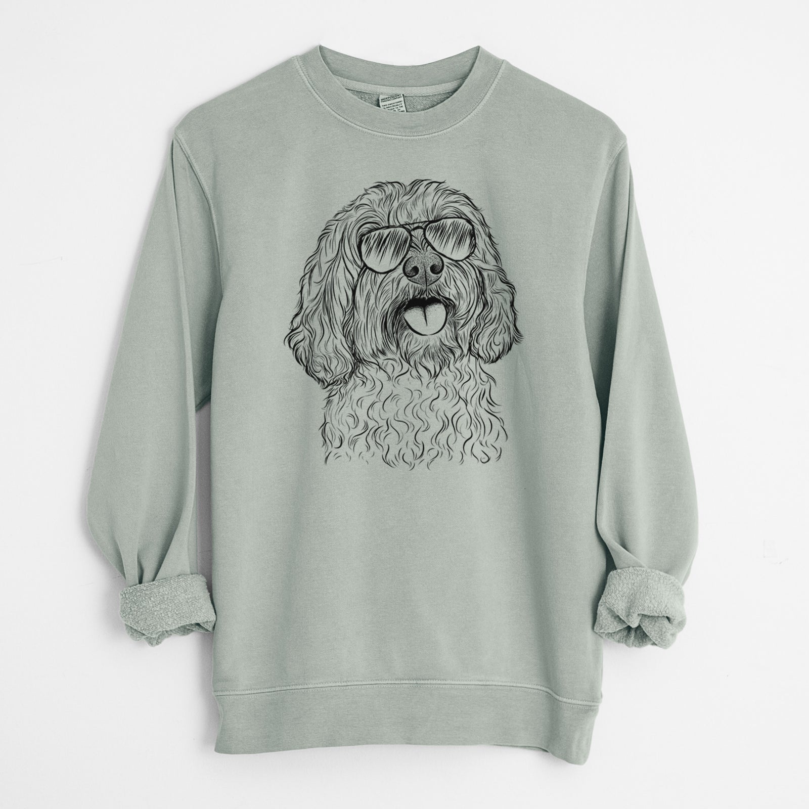 Hand-drawn sketch of Cali the Cavapoo wearing aviator sunglasses on a Sage Unisex pigment dyed crew sweatshirt