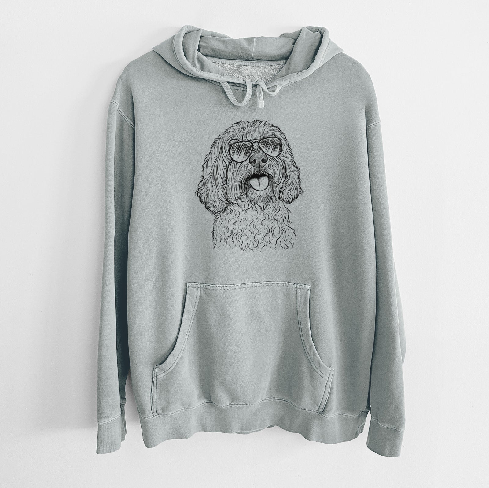 Hand-drawn sketch of Cali the Cavapoo wearing aviator sunglasses on a Sage Unisex pigment dyed hoodie