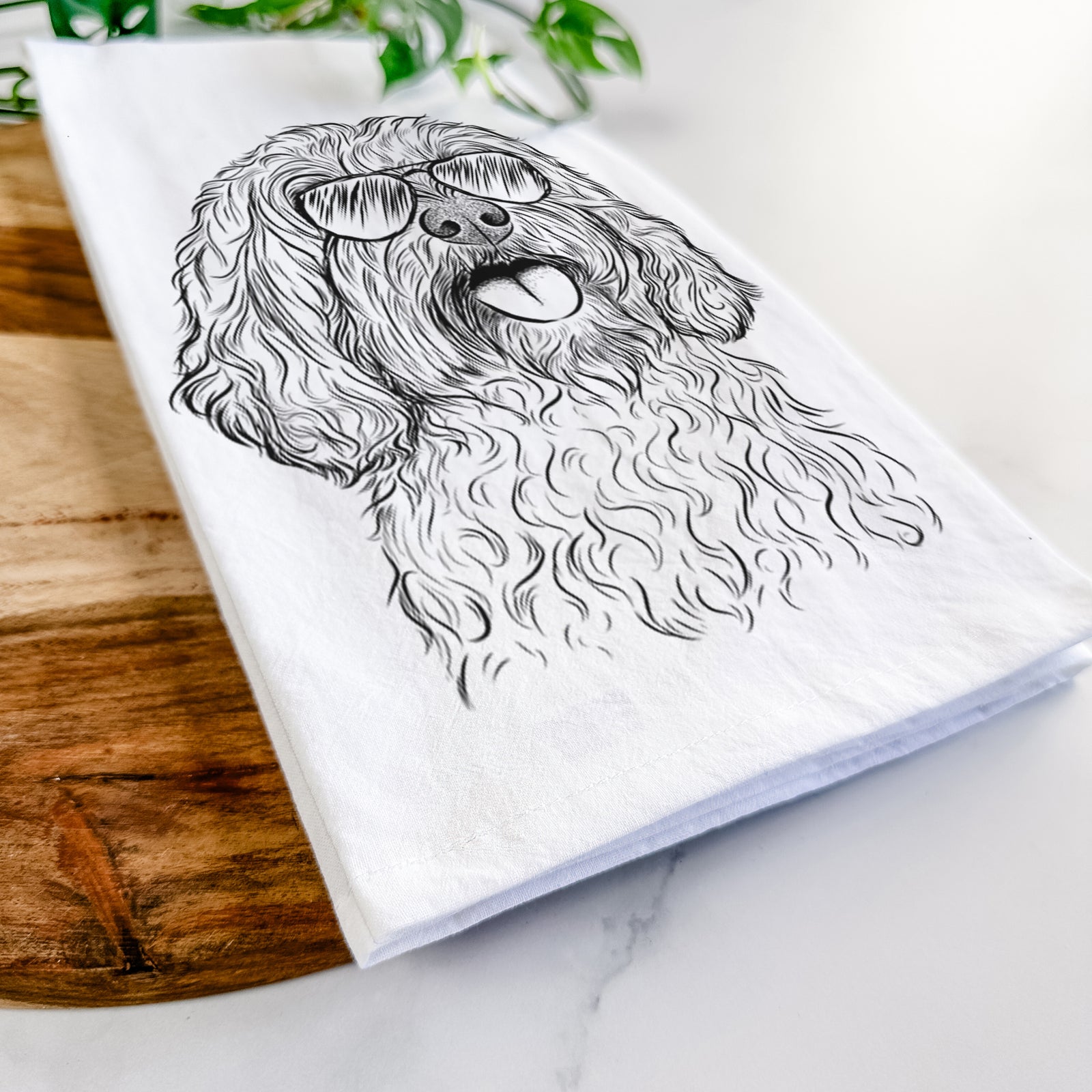 Hand-drawn sketch of Cali the Cavapoo wearing aviator sunglasses on a tea towel