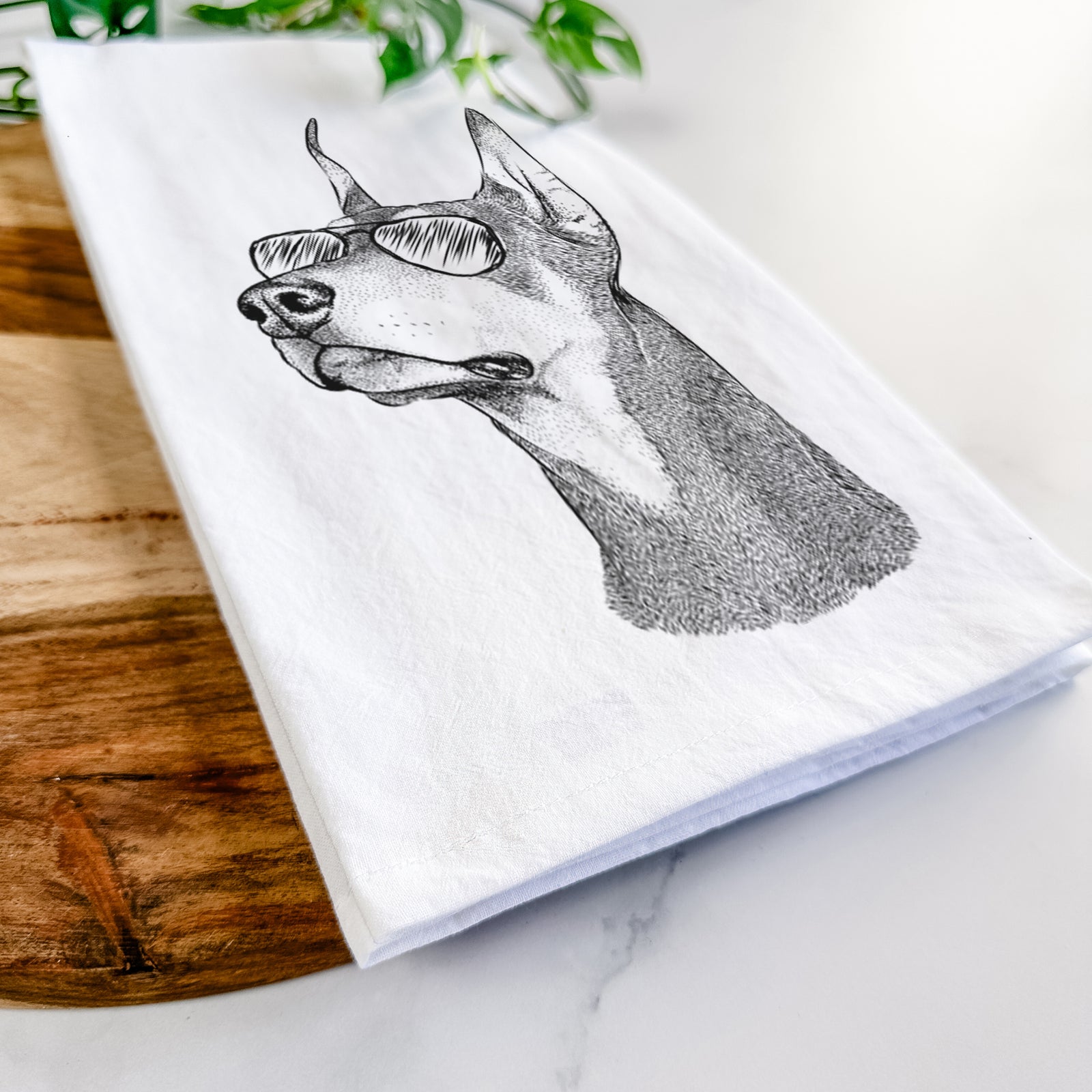 Hand-drawn sketch of Cenza the Doberman Pinscher wearing aviator sunglasses on a tea towel
