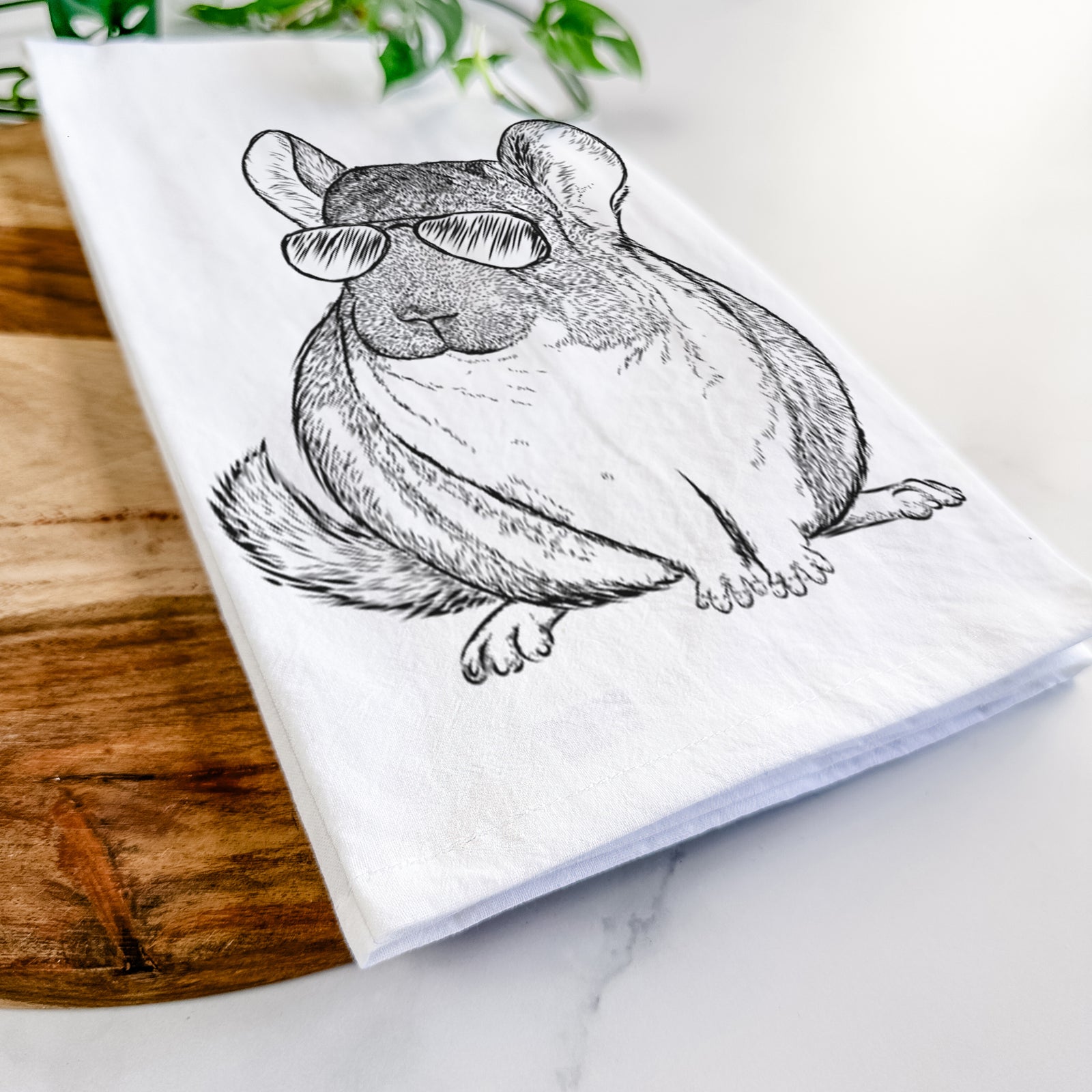 Hand-drawn sketch of Cheddar the Chinchilla wearing aviator sunglasses on a tea towel