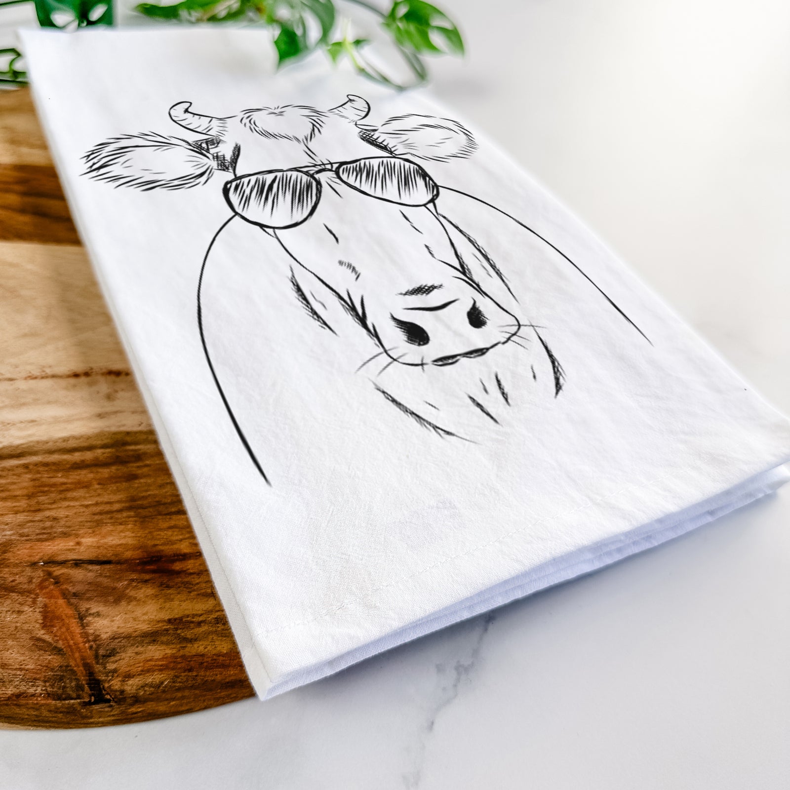 Hand-drawn sketch of Cruz the Cow wearing aviator sunglasses on a tea towel