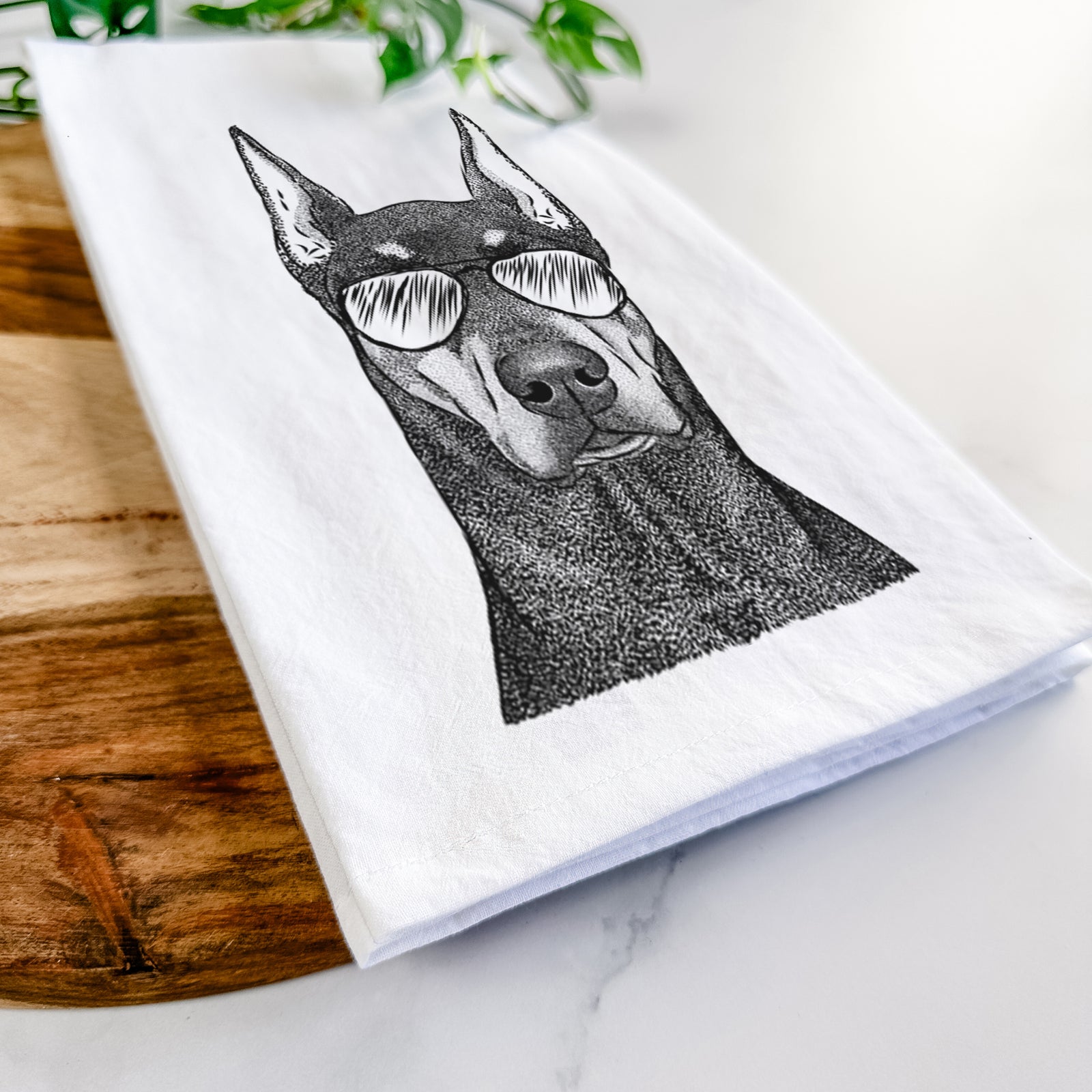 Hand-drawn sketch of Drake the Doberman Pinscher wearing aviator sunglasses on a tea towel