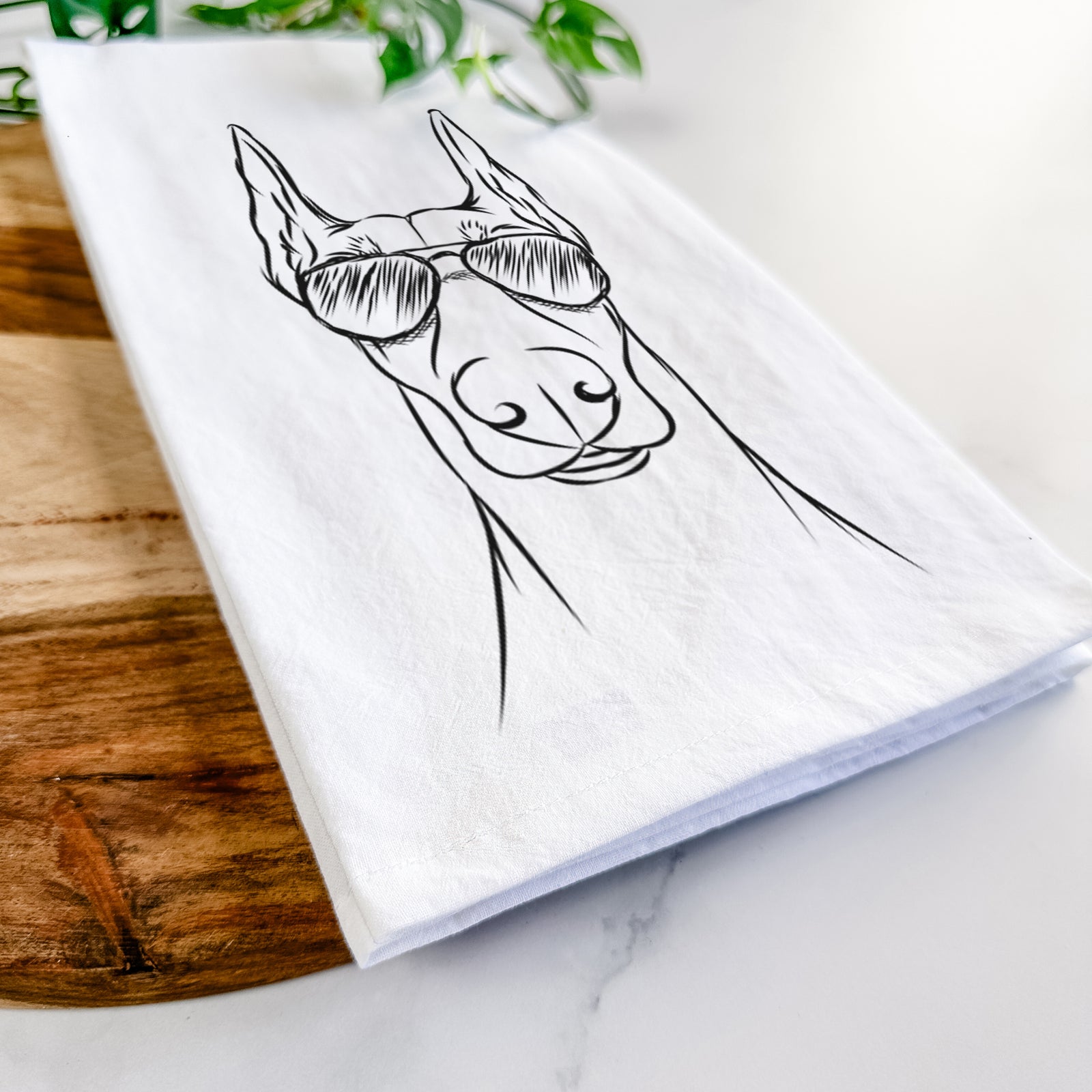 Hand-drawn sketch of Duke the Doberman Pinscher wearing aviator sunglasses on a tea towel