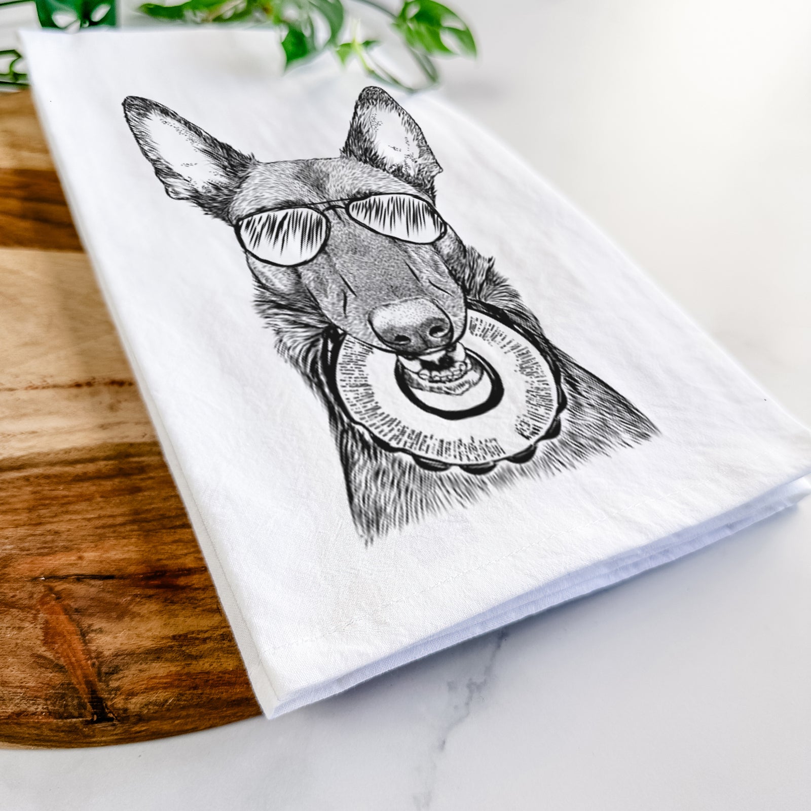 Hand-drawn sketch of Juno the Belgian Malinois wearing aviator sunglasses on a tea towel