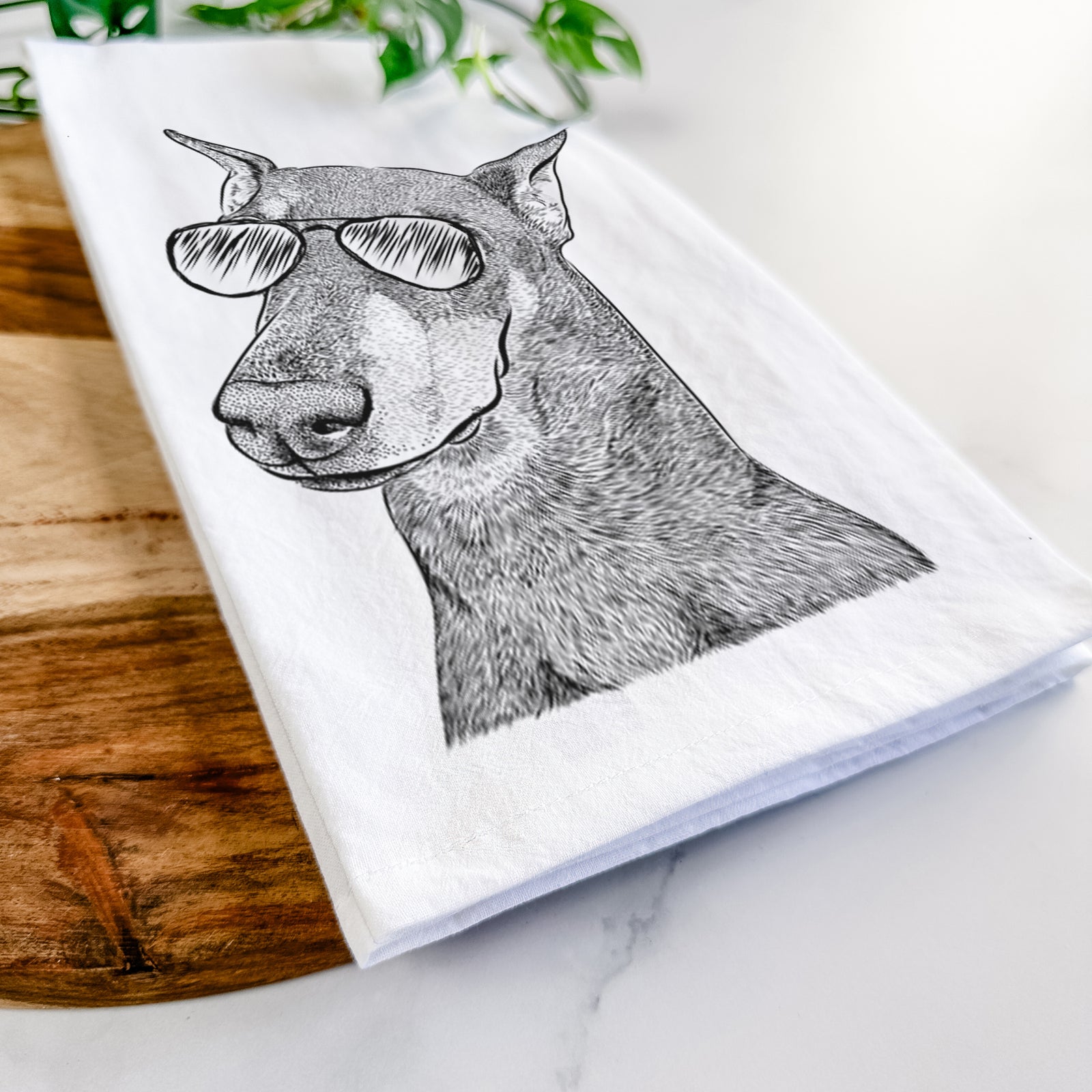 Hand-drawn sketch of Shelby the Doberman Pinscher wearing aviator sunglasses on a tea towel