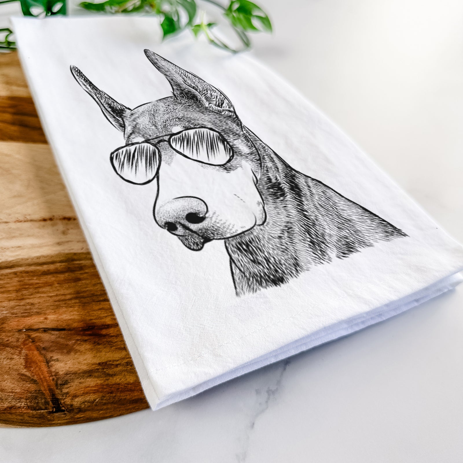 Hand-drawn sketch of Sunny the Doberman Pinscher wearing aviator sunglasses on a tea towel