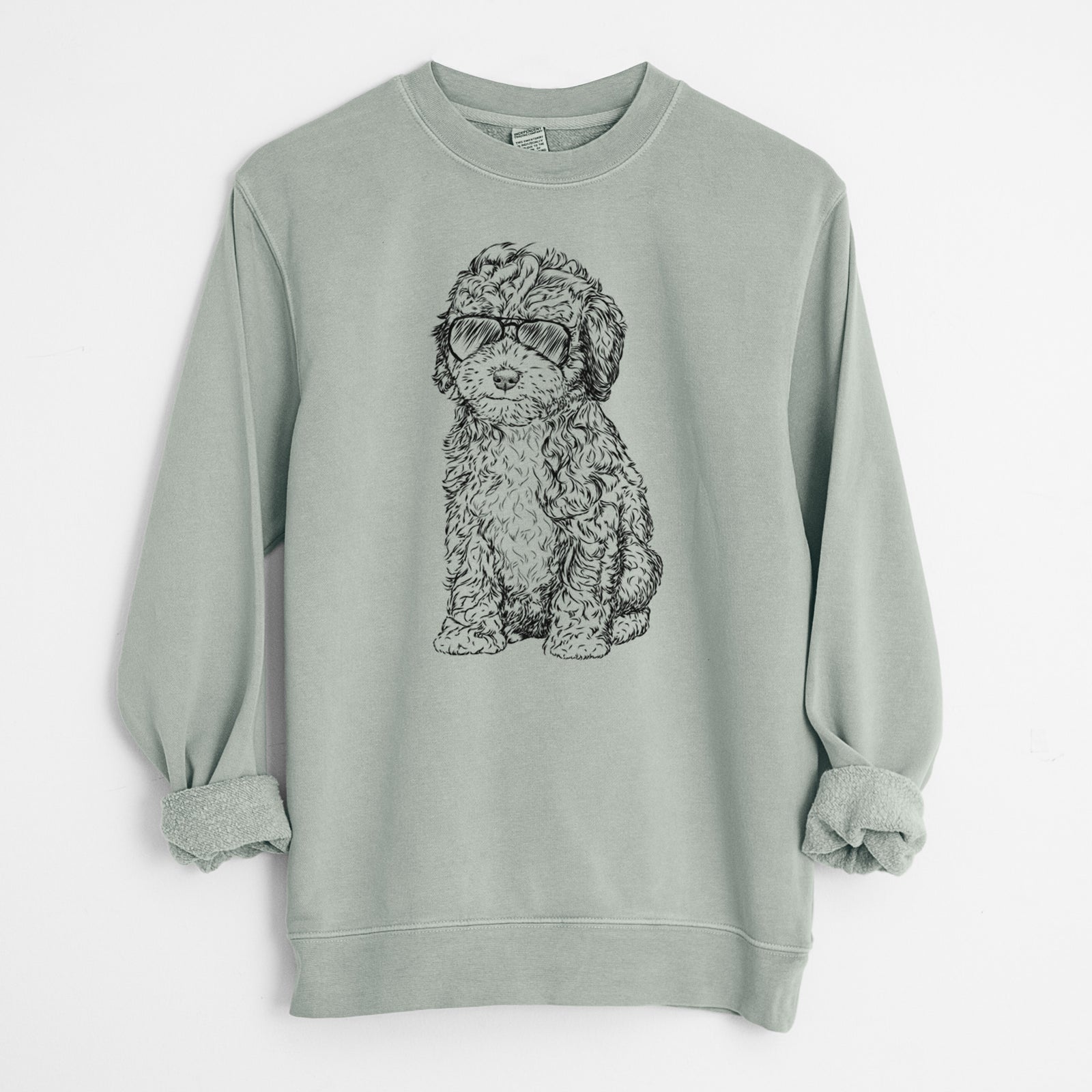 Hand-drawn sketch of Sweet Tea the Mini Doodle wearing aviator sunglasses on a Sage Unisex pigment dyed crew sweatshirt