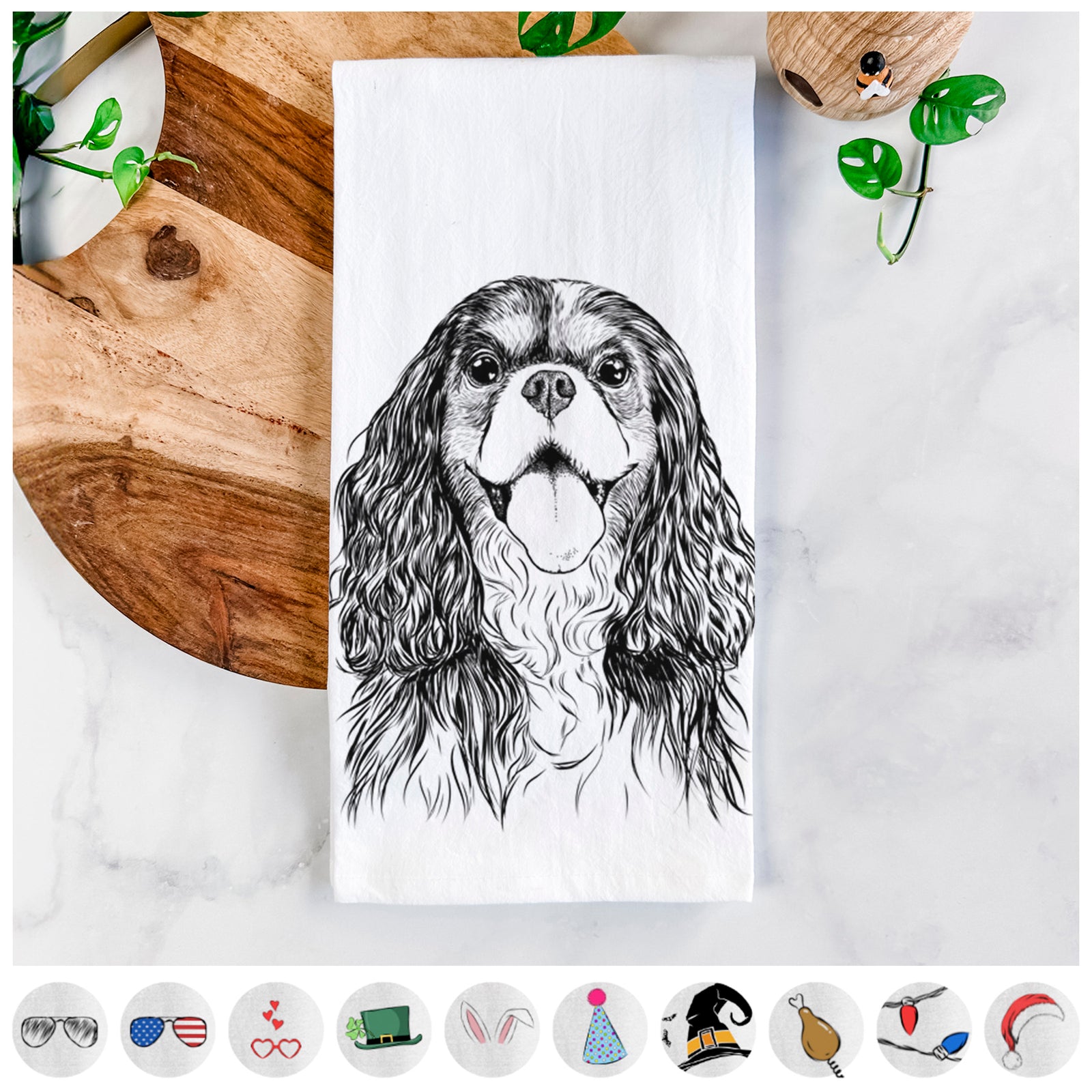 Hand-drawn sketch of Brandy the Cavalier King Charles Spaniel on a tea towel, shown with icons of the other available costume styles