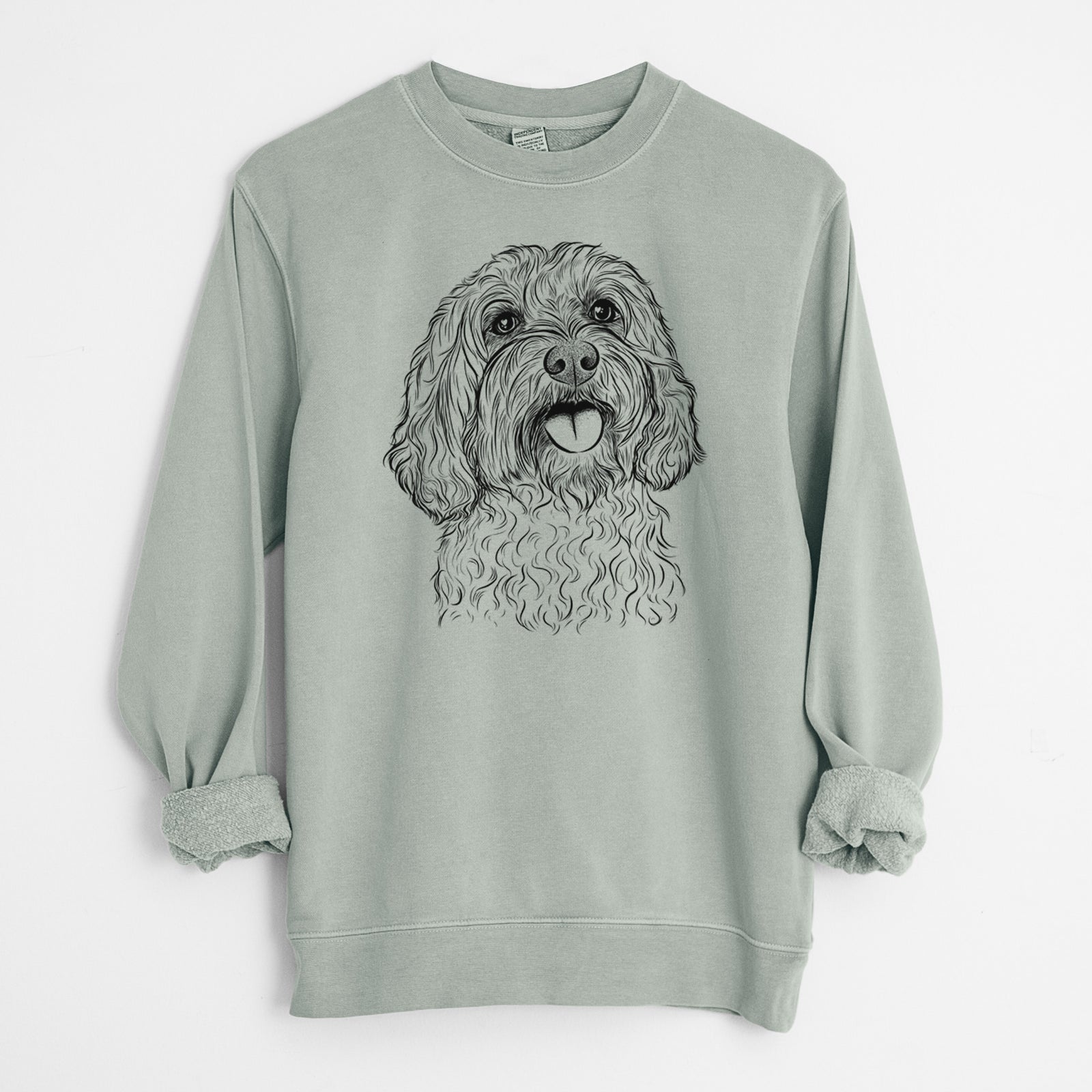Hand-drawn sketch of Cali the Cavapoo on a Sage Unisex pigment dyed crew sweatshirt