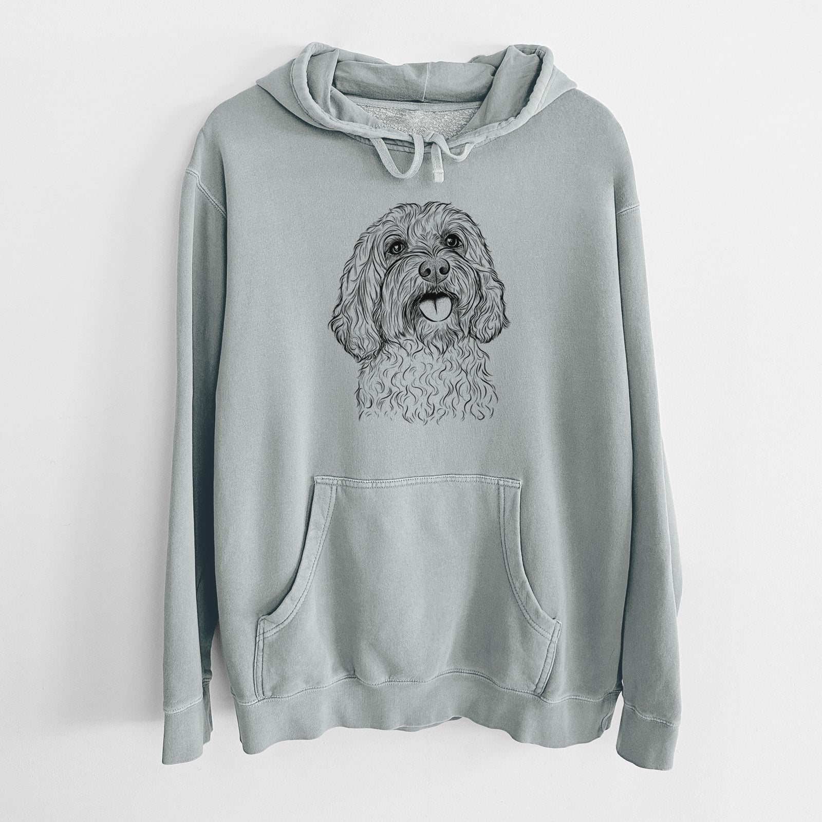 Hand-drawn sketch of Cali the Cavapoo on a Sage Unisex pigment dyed hoodie
