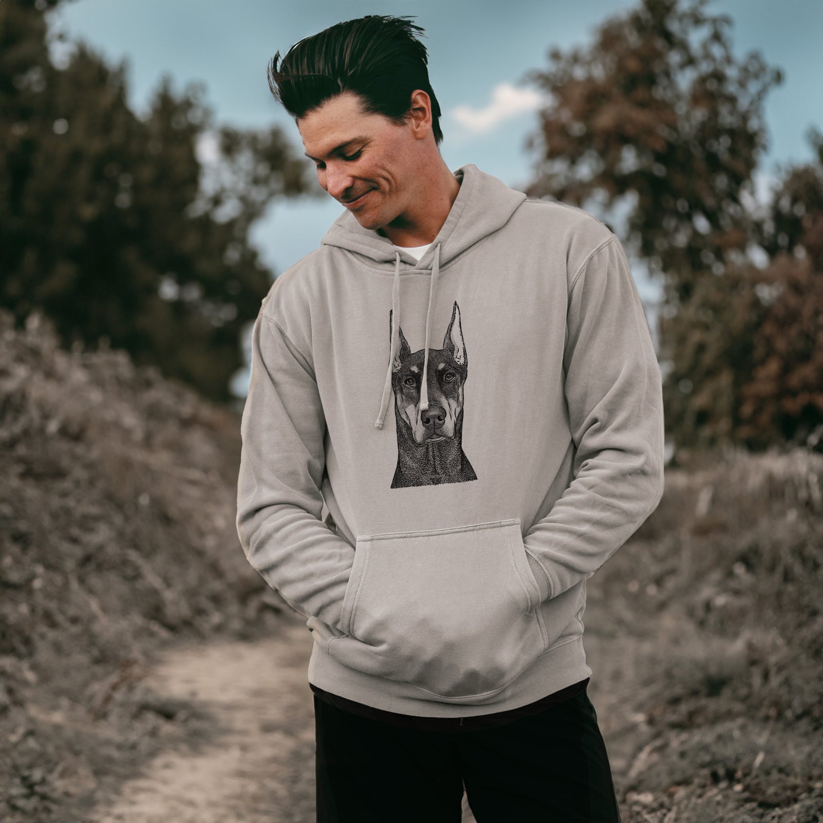 Hand-drawn sketch of Drake the Doberman Pinscher on a Cement Unisex pigment dyed hoodie, worn by a man