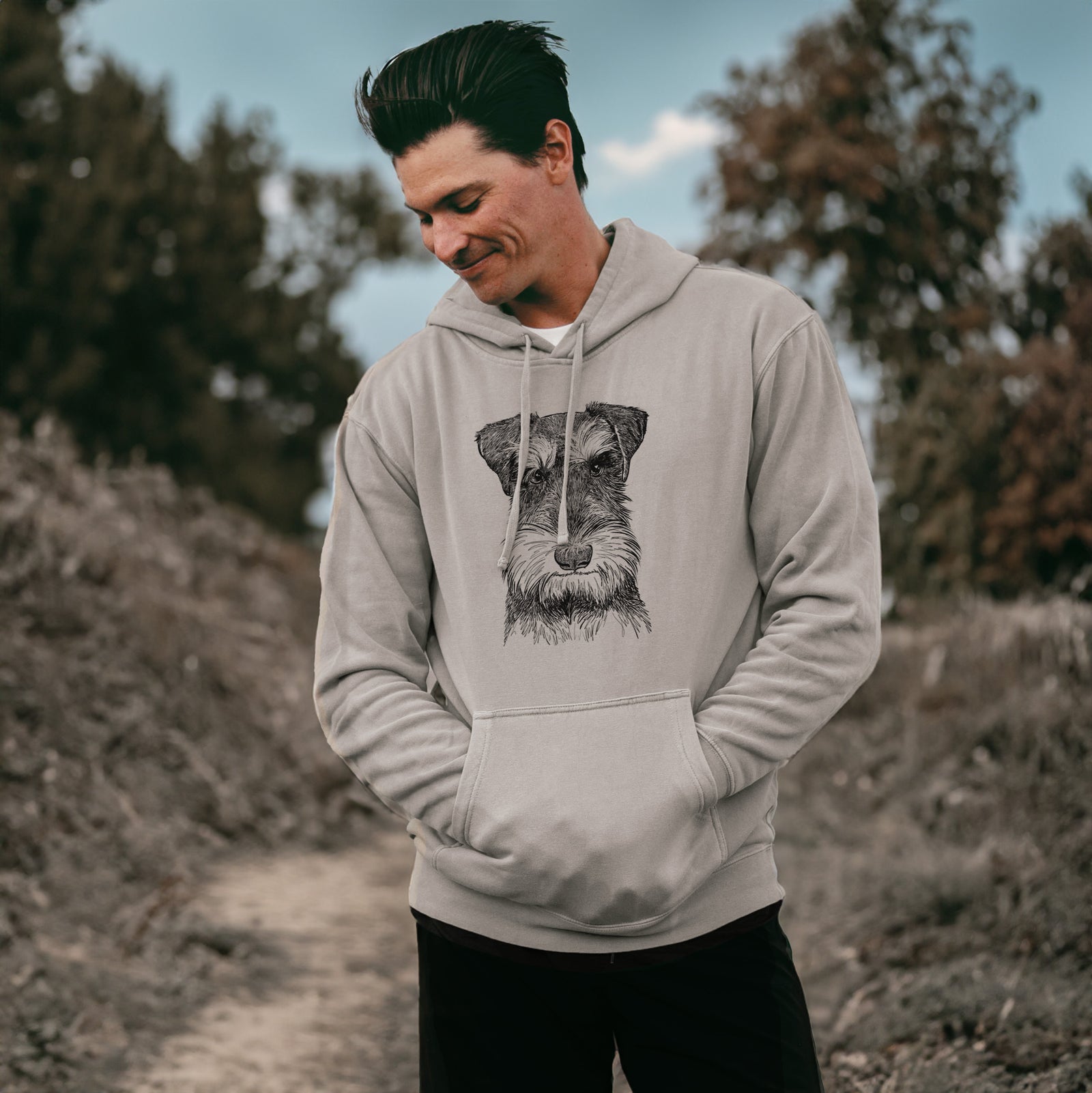 Hand-drawn sketch of Murphy the Mini Schnauzer on a Cement Unisex pigment dyed hoodie, worn by a man