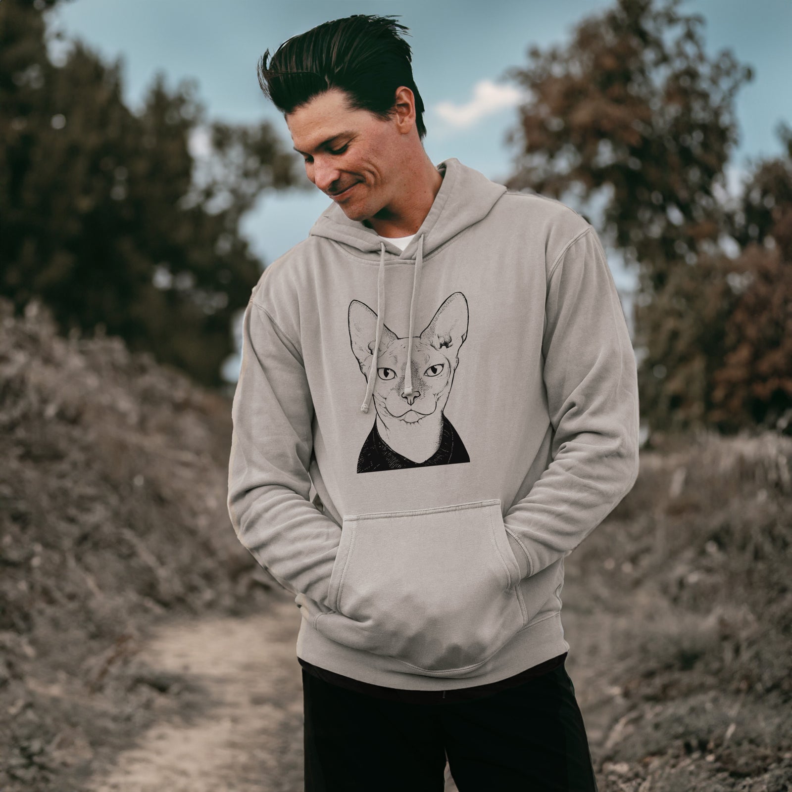 Hand-drawn sketch of Oliver Watson the Sphynx Cat on a Cement Unisex pigment dyed hoodie, worn by a man