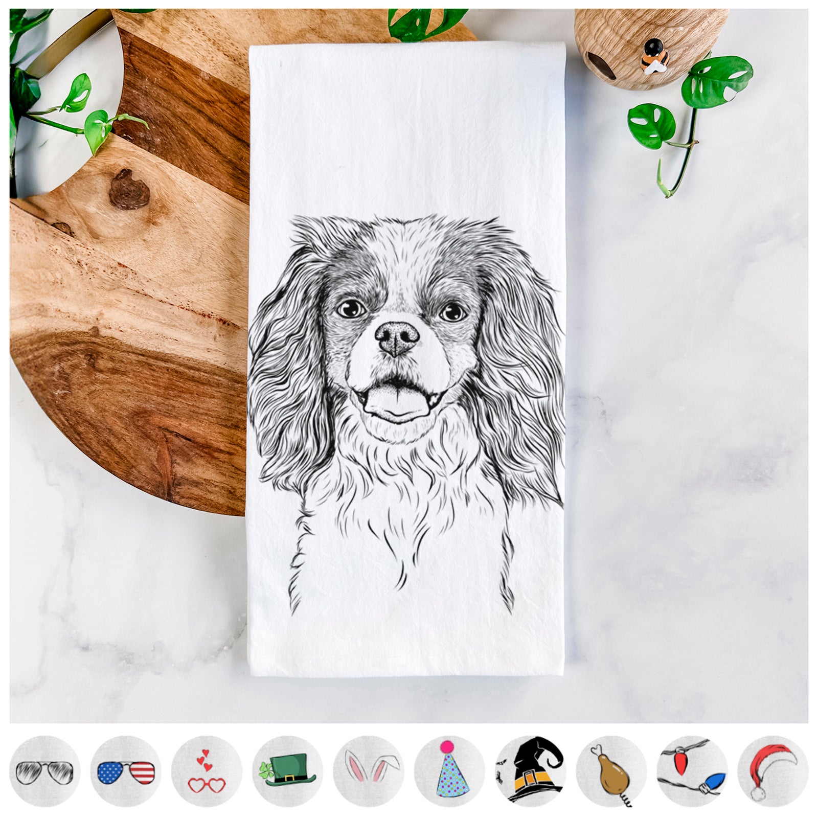 Hand-drawn sketch of Poppy the Cavalier King Charles Spaniel on a tea towel, shown with icons of the other available costume styles