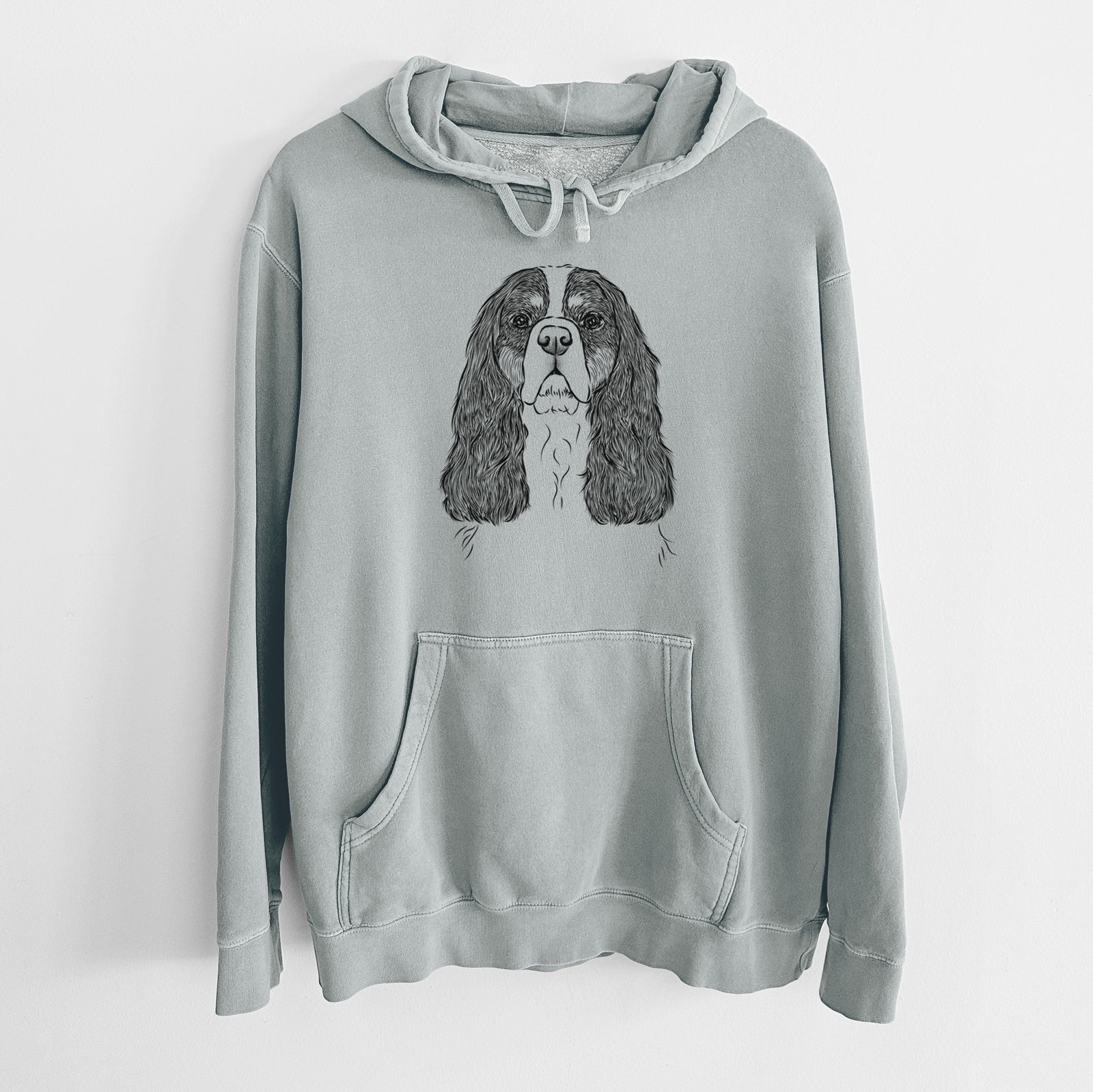 Hand-drawn sketch of Sebastian the Cavalier King Charles Spaniel on a Sage Unisex pigment dyed hoodie