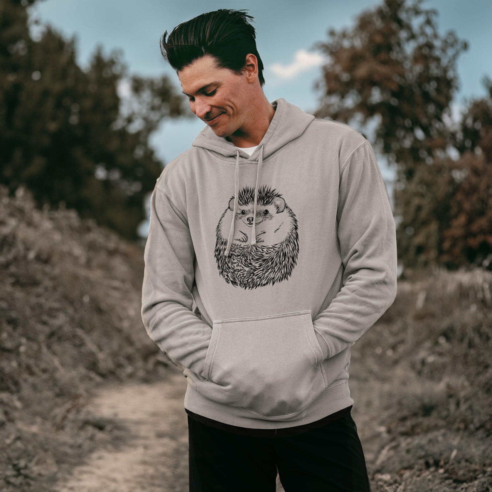 Hand-drawn sketch of Sid the Hedgehog on a Cement Unisex pigment dyed hoodie, worn by a man