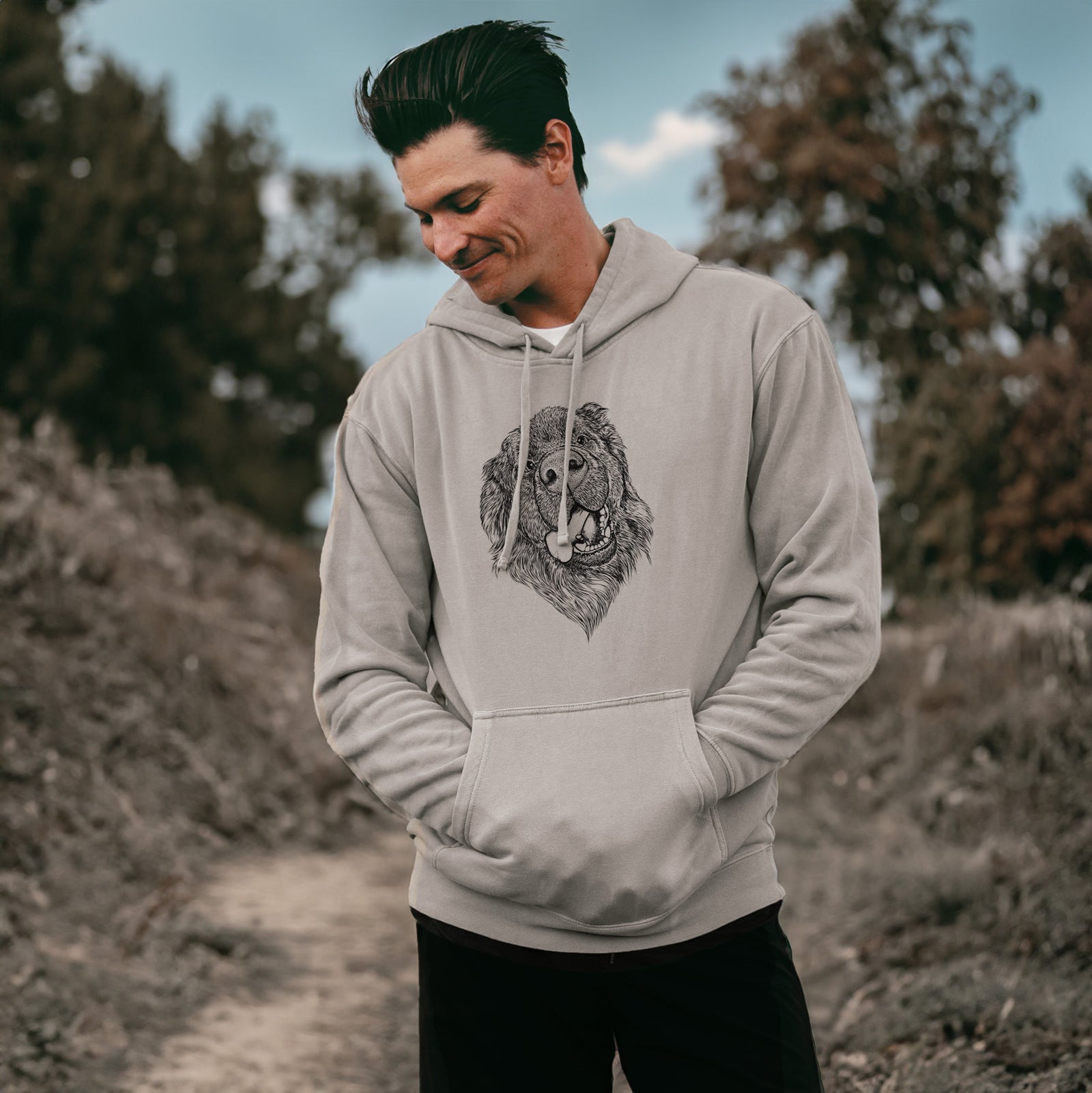 Hand-drawn sketch of Tuna the Newfoundland on a Cement Unisex pigment dyed hoodie, worn by a man