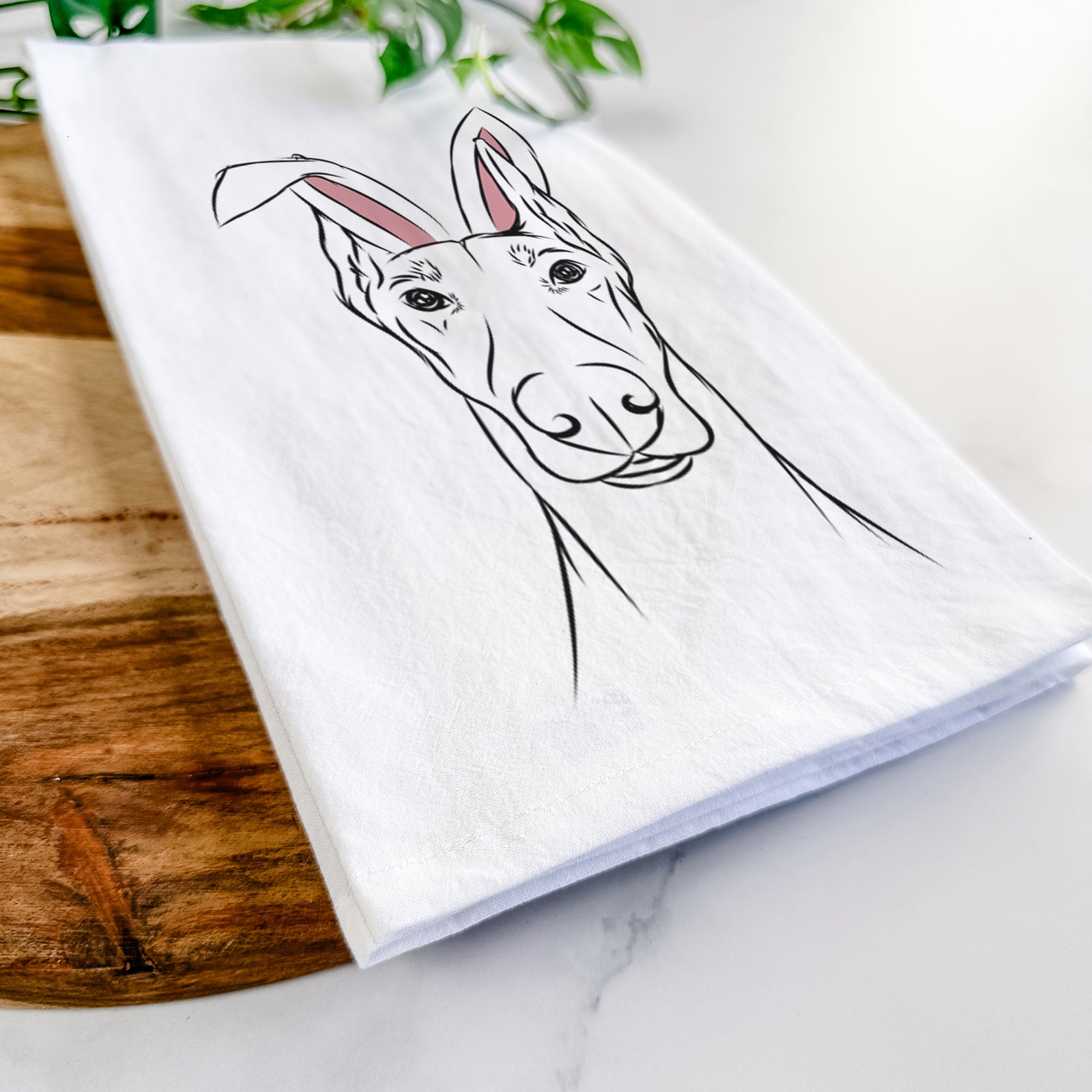 Hand-drawn sketch of Duke the Doberman Pinscher wearing Easter bunny ears on a tea towel