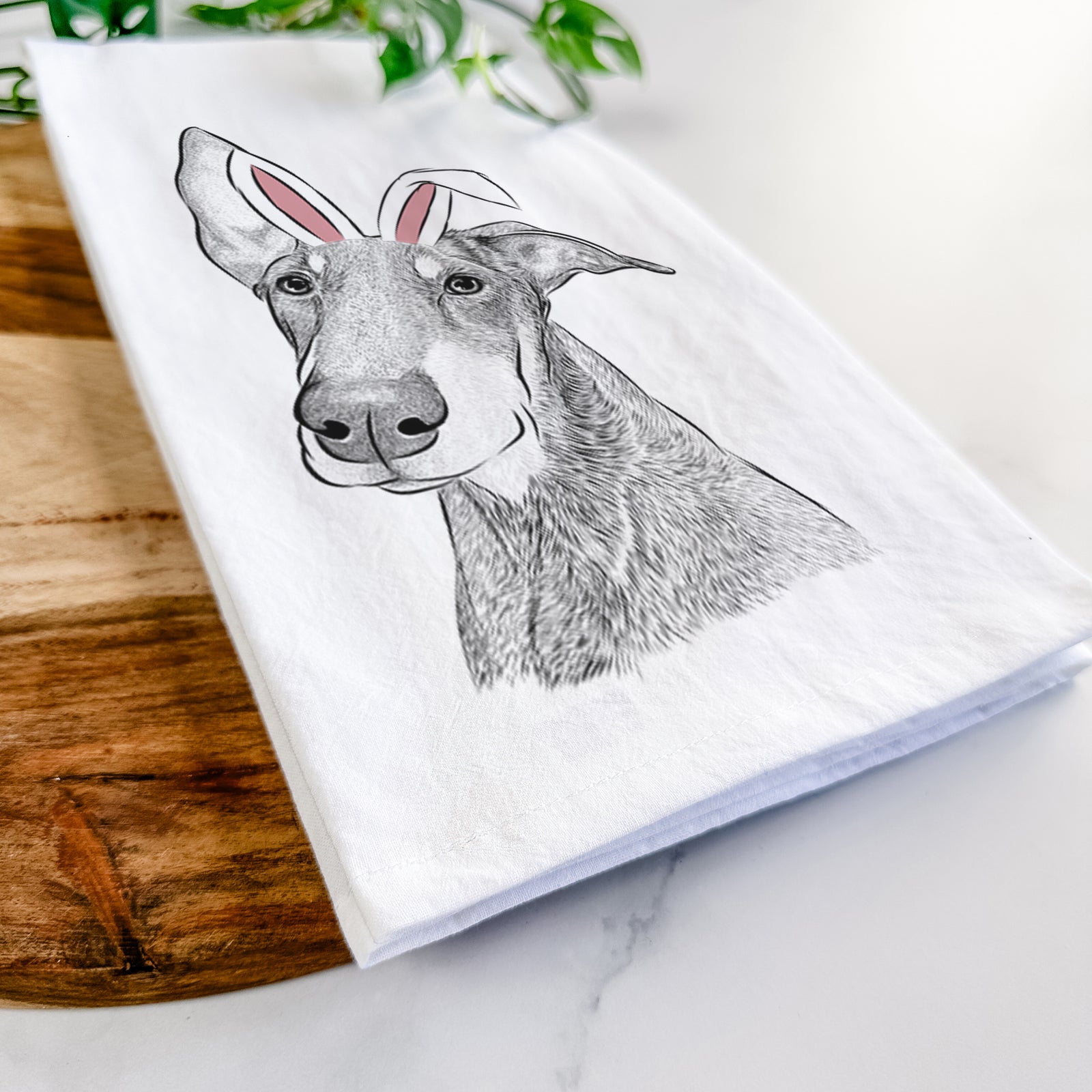 Hand-drawn sketch of Kain the Doberman Pinscher wearing Easter bunny ears on a tea towel