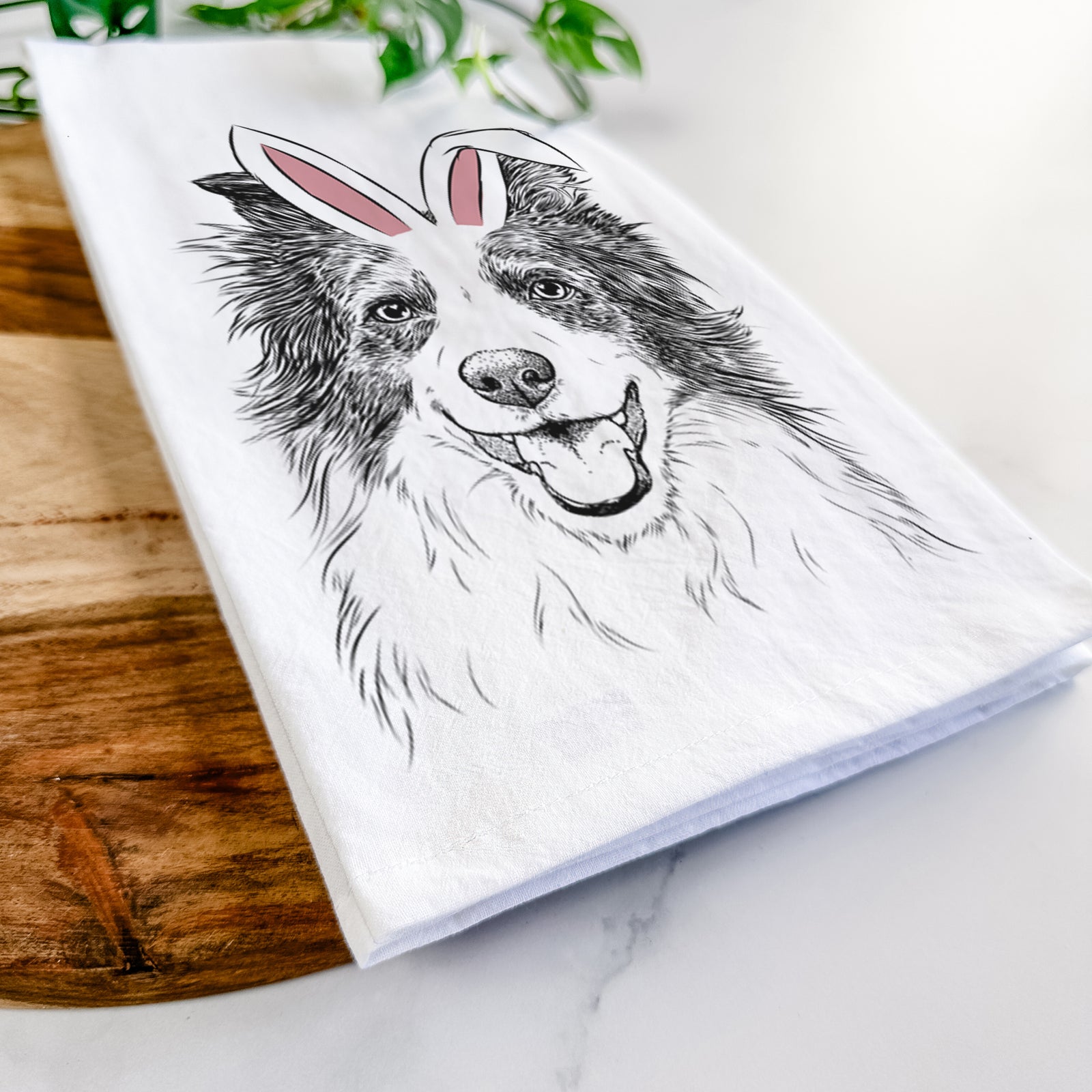 Hand-drawn sketch of Kylee the Border Collie wearing Easter bunny ears on a tea towel