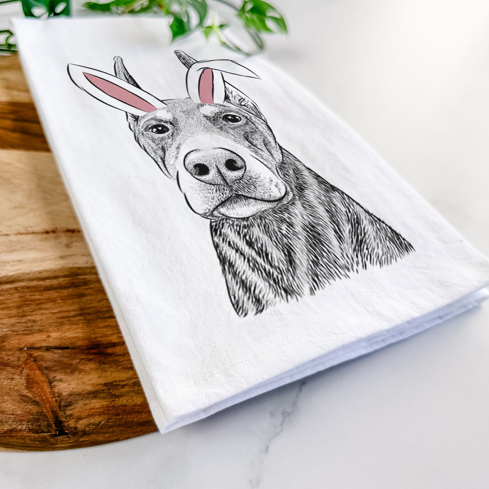 Hand-drawn sketch of Luna the Doberman Pinscher wearing Easter bunny ears on a tea towel