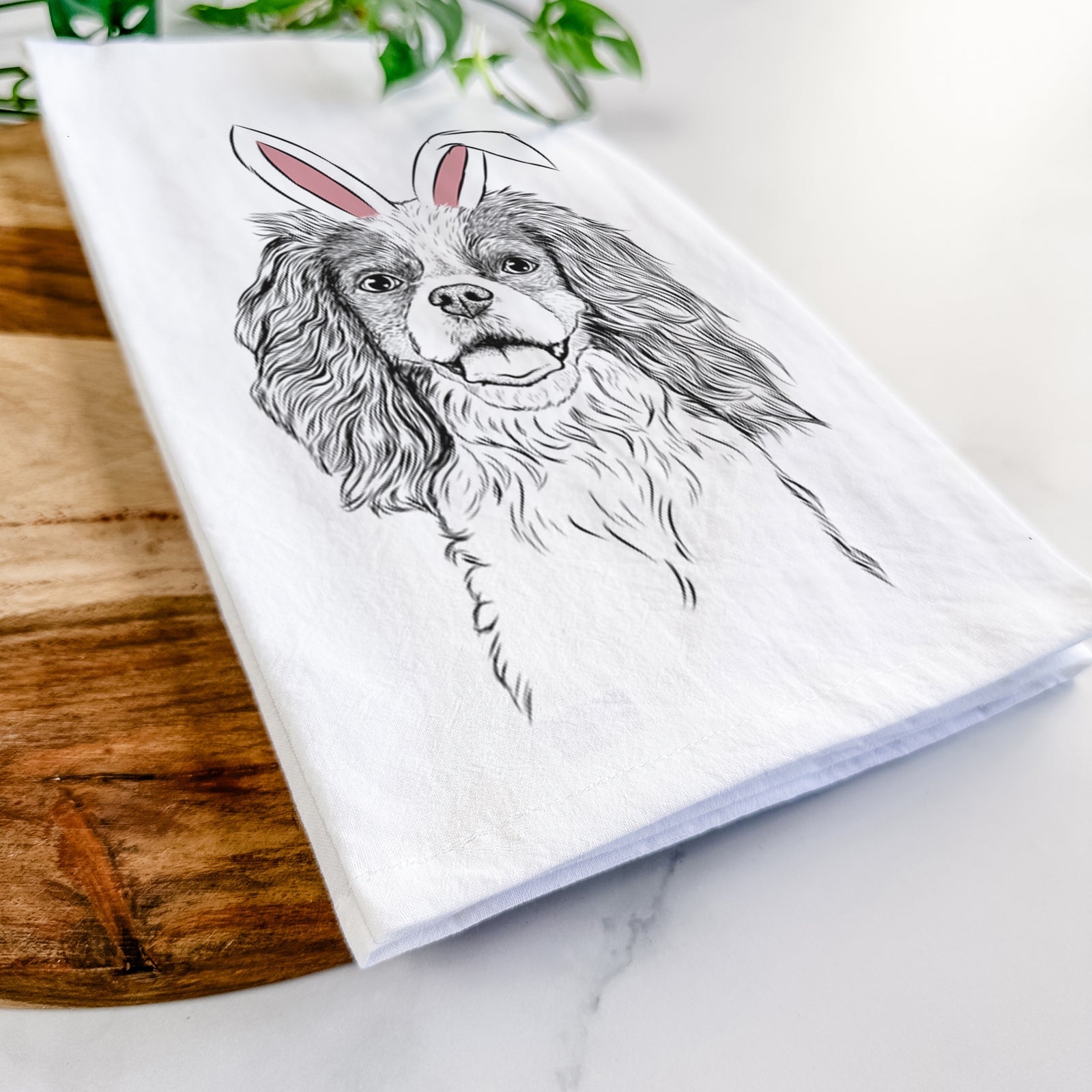 Hand-drawn sketch of Poppy the Cavalier King Charles Spaniel wearing Easter bunny ears on a tea towel
