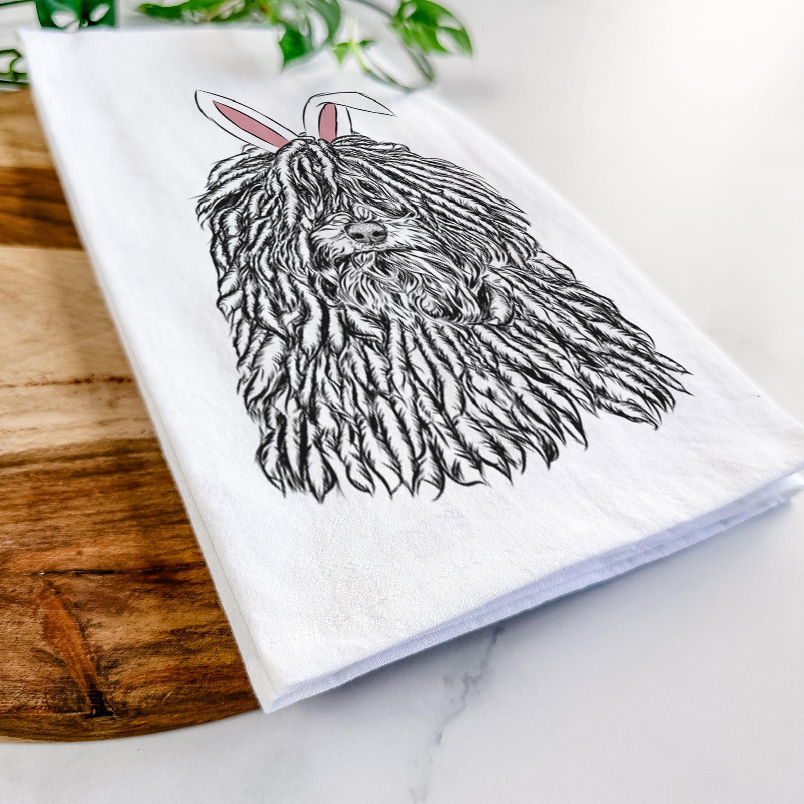 Hand-drawn sketch of Rezi the Puli wearing Easter bunny ears on a tea towel