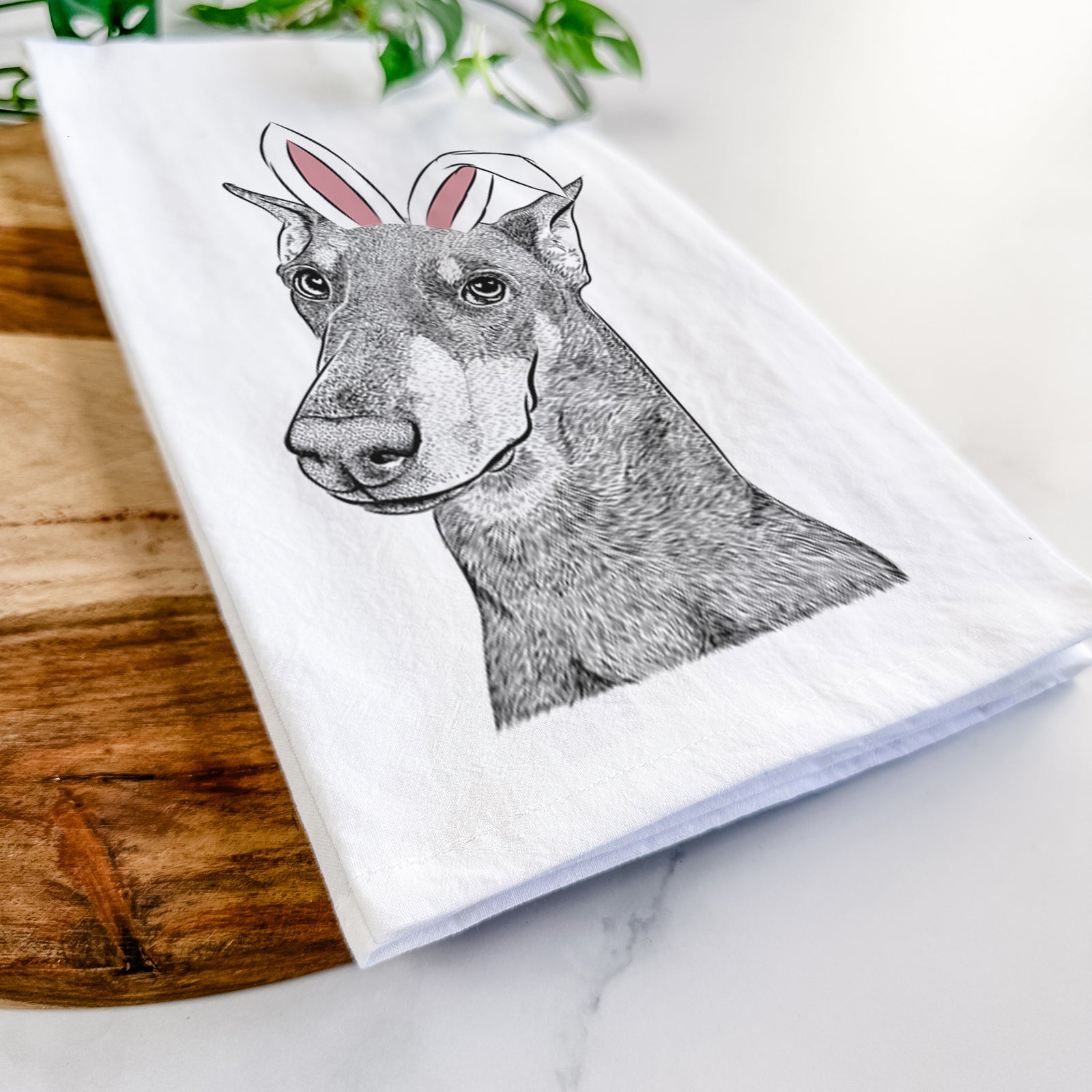Hand-drawn sketch of Shelby the Doberman Pinscher wearing Easter bunny ears on a tea towel