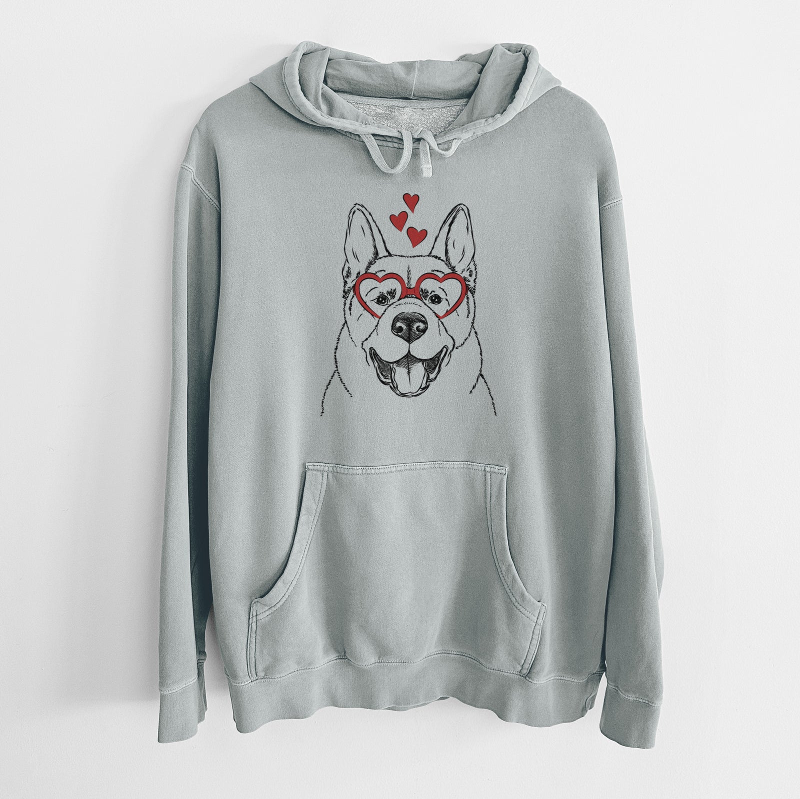 Hand-drawn sketch of Baku the Akita wearing heart-shaped glasses on a Sage Unisex pigment dyed hoodie