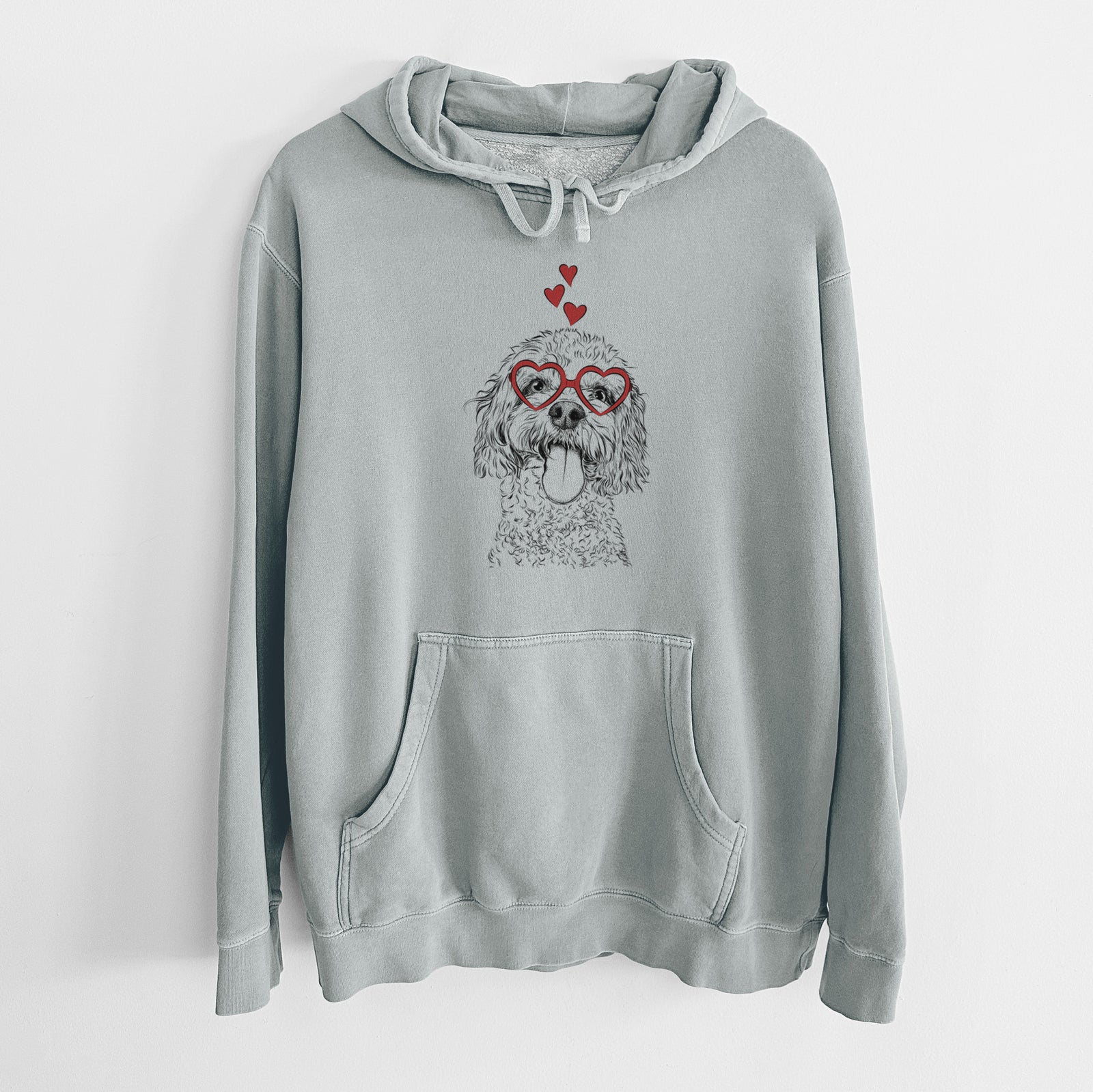 Hand-drawn sketch of Barney the Cavachon wearing heart-shaped glasses on a Sage Unisex pigment dyed hoodie