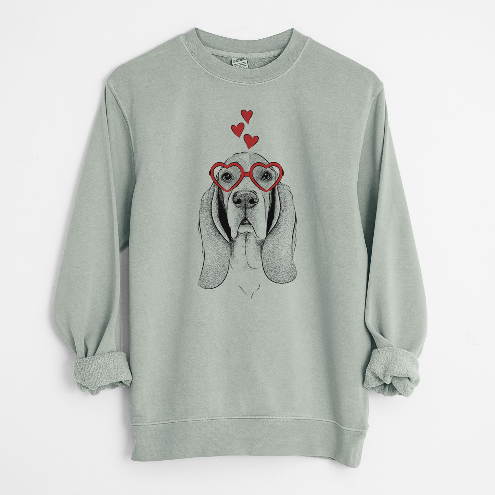 Hand-drawn sketch of Buckley the Basset Hound wearing heart-shaped glasses on a Sage Unisex pigment dyed crew sweatshirt