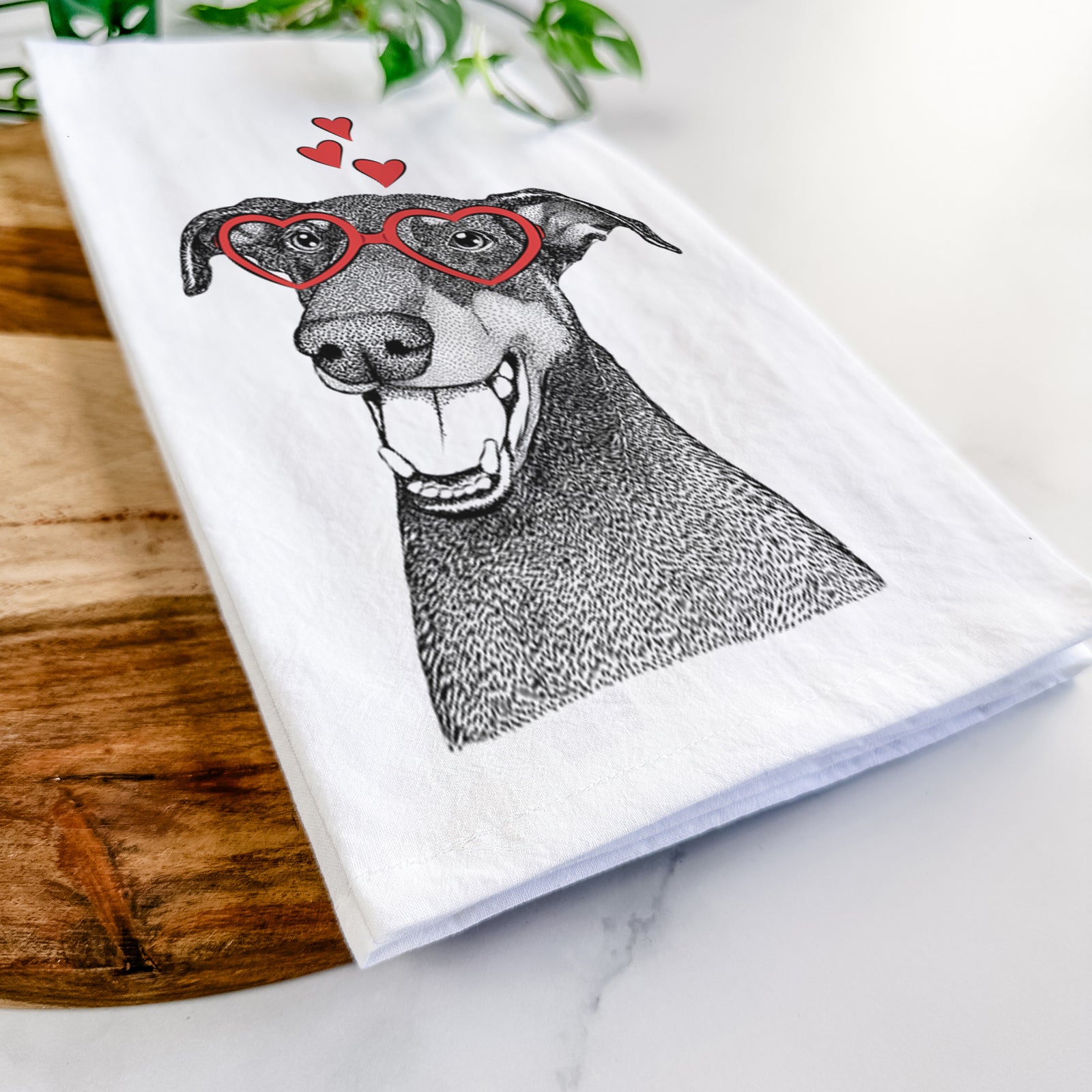Hand-drawn sketch of Bunnie the Doberman Pinscher wearing heart-shaped glasses on a tea towel