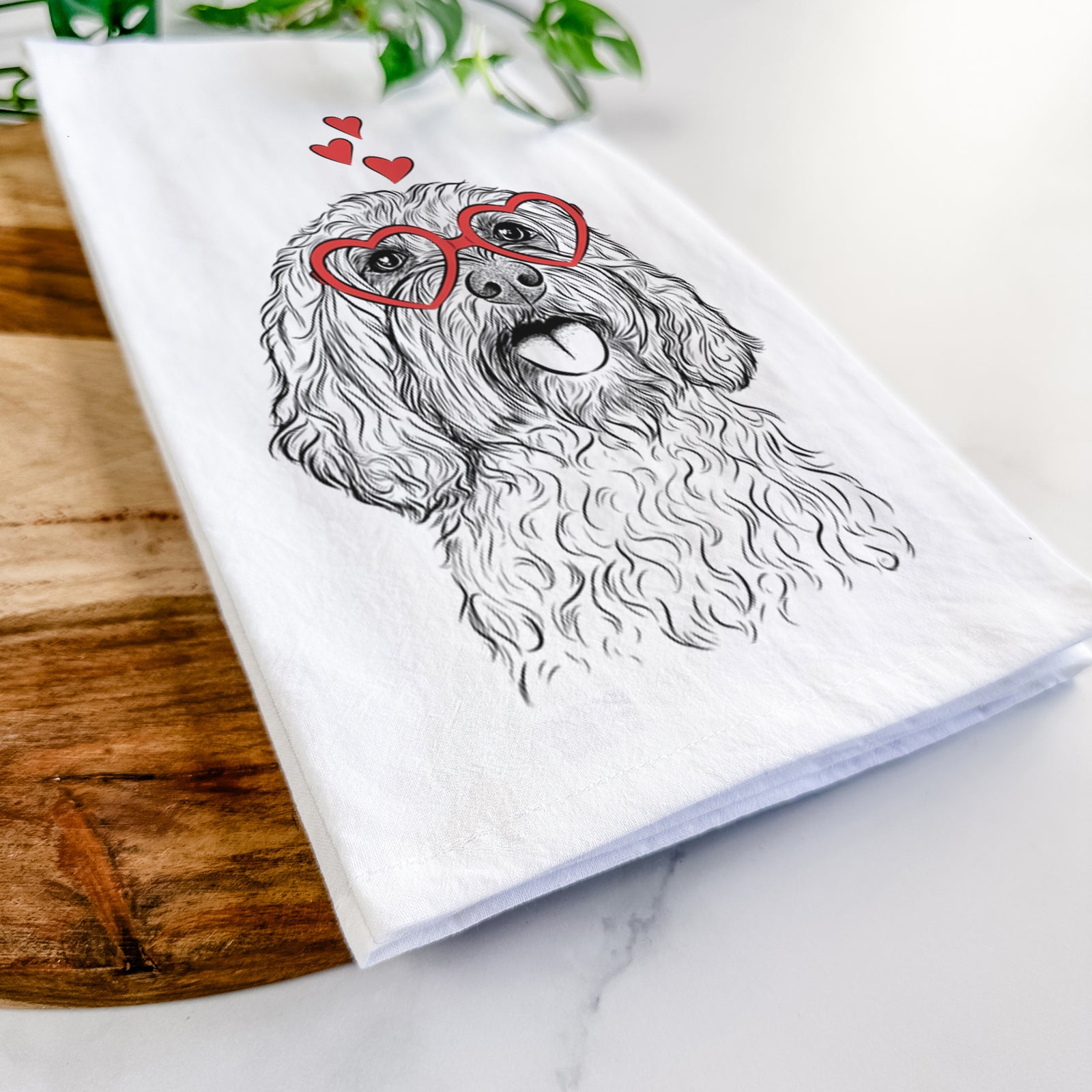 Hand-drawn sketch of Cali the Cavapoo wearing heart-shaped glasses on a tea towel