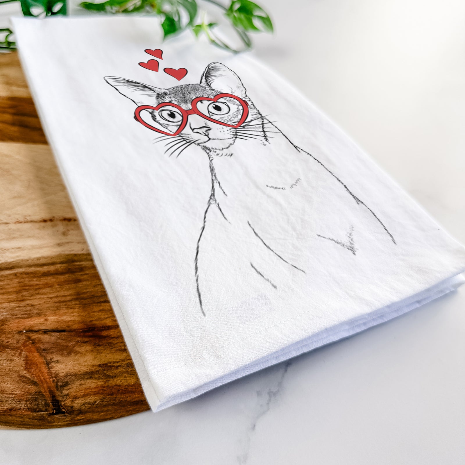 Hand-drawn sketch of Cedric the Abyssinian Cat wearing heart-shaped glasses on a tea towel