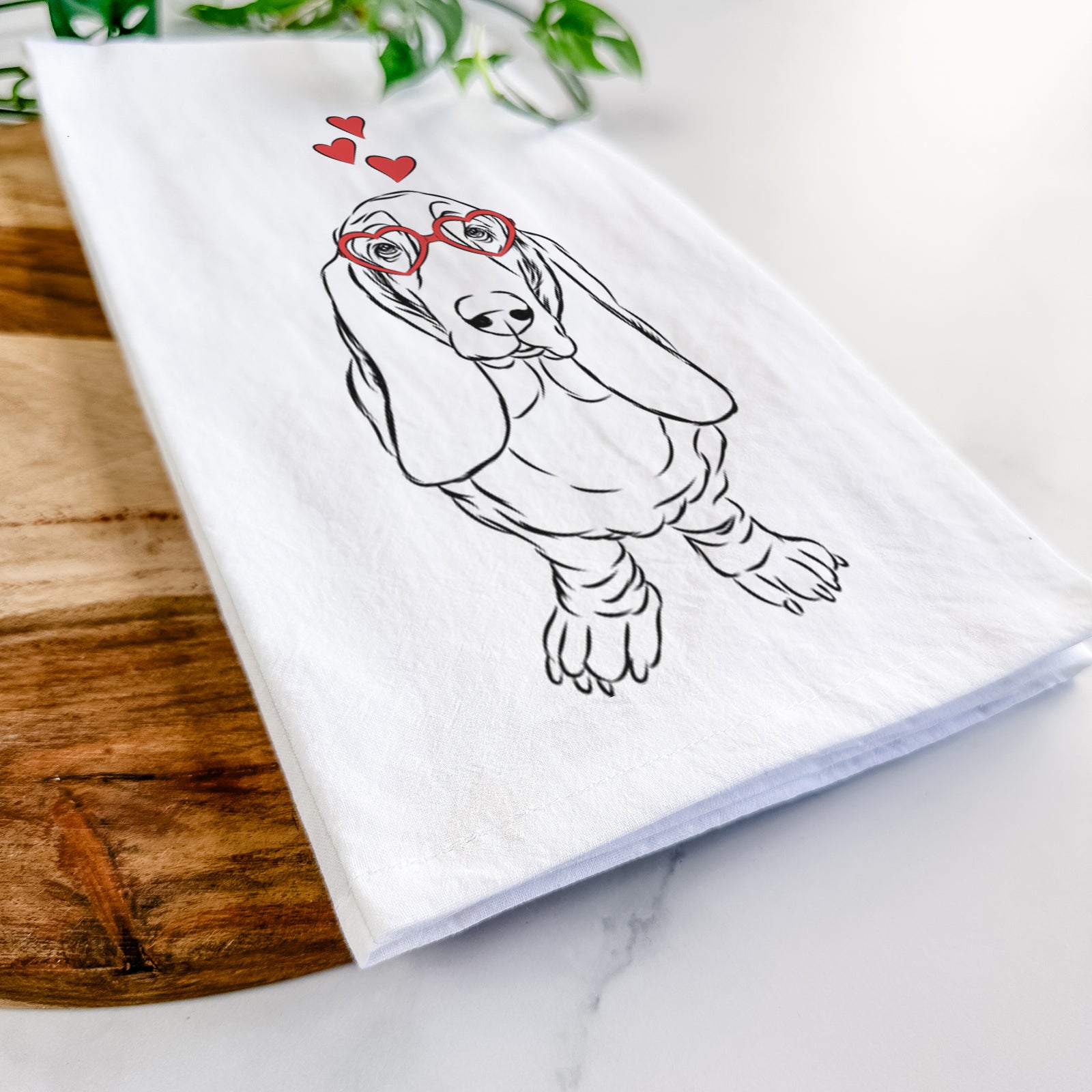 Hand-drawn sketch of Charlie the Basset Hound wearing heart-shaped glasses on a tea towel