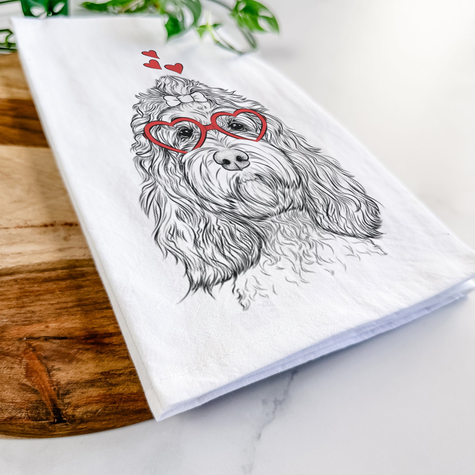 Hand-drawn sketch of Chloe the Cockapoo wearing heart-shaped glasses on a tea towel