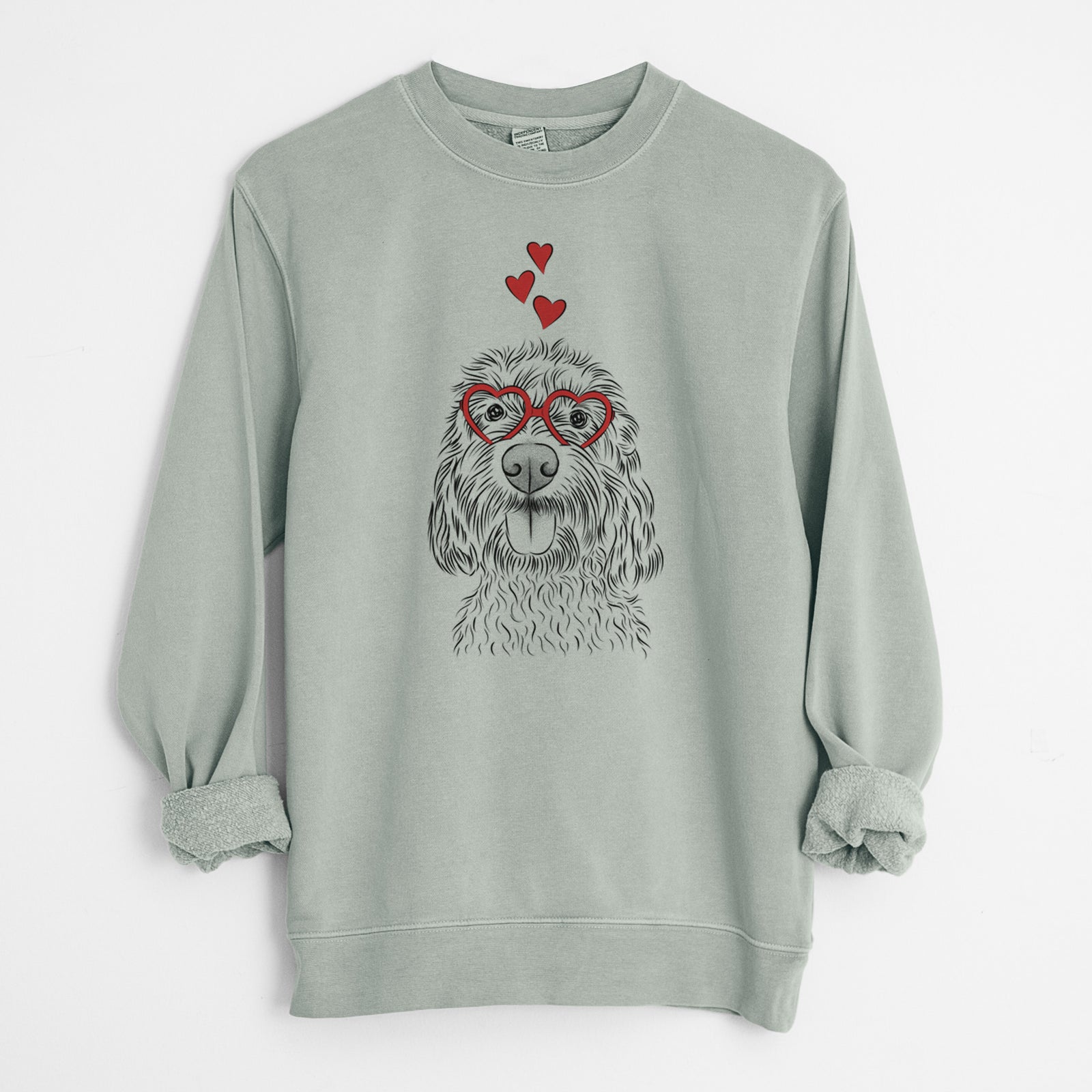 Hand-drawn sketch of Clover the Cockapoo wearing heart-shaped glasses on a Sage Unisex pigment dyed crew sweatshirt