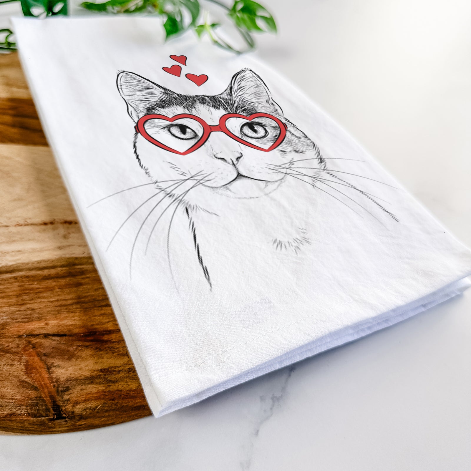 Hand-drawn sketch of Denver the Calico Cat wearing heart-shaped glasses on a tea towel