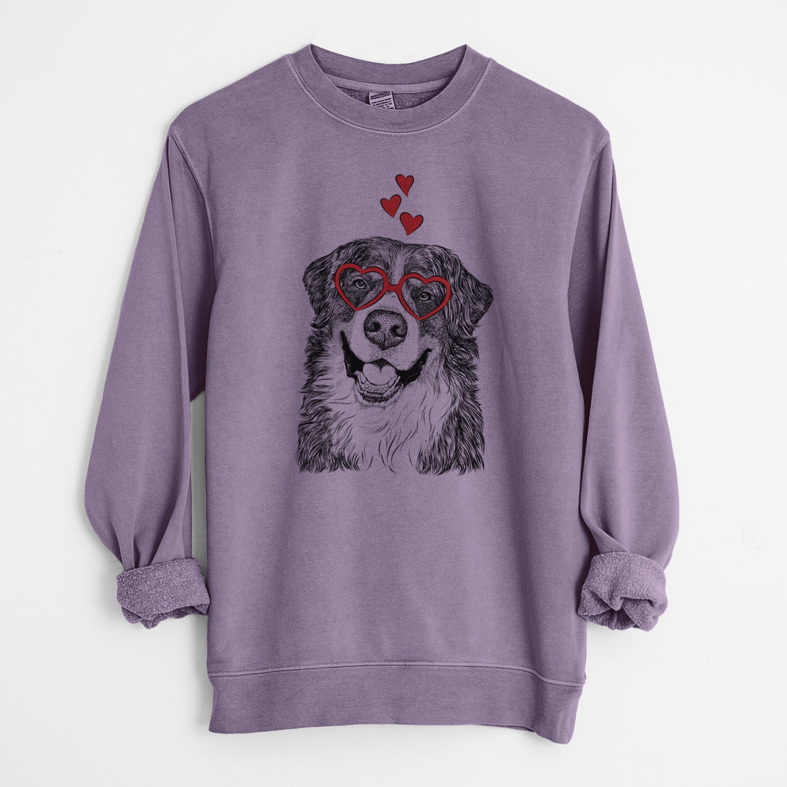 Hand-drawn sketch of Eiger the Bernese Mountain Dog wearing heart-shaped glasses on a Plum Unisex pigment dyed crew sweatshirt