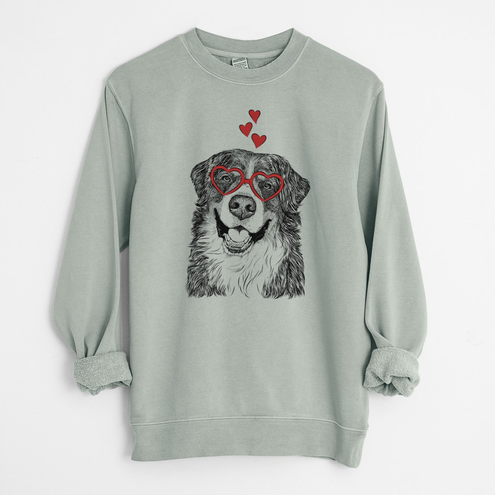 Hand-drawn sketch of Eiger the Bernese Mountain Dog wearing heart-shaped glasses on a Sage Unisex pigment dyed crew sweatshirt