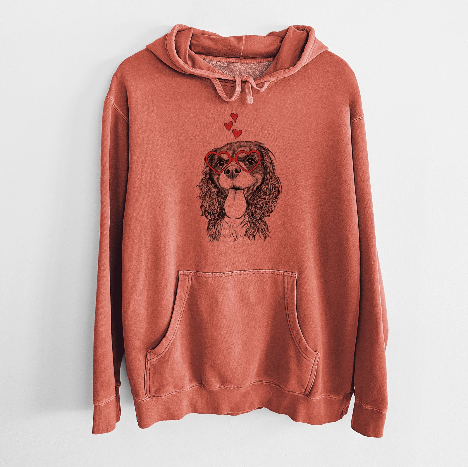 Hand-drawn sketch of Elizabeth the Cavalier King Charles Spaniel wearing heart-shaped glasses on an Amber Unisex pigment dyed hoodie