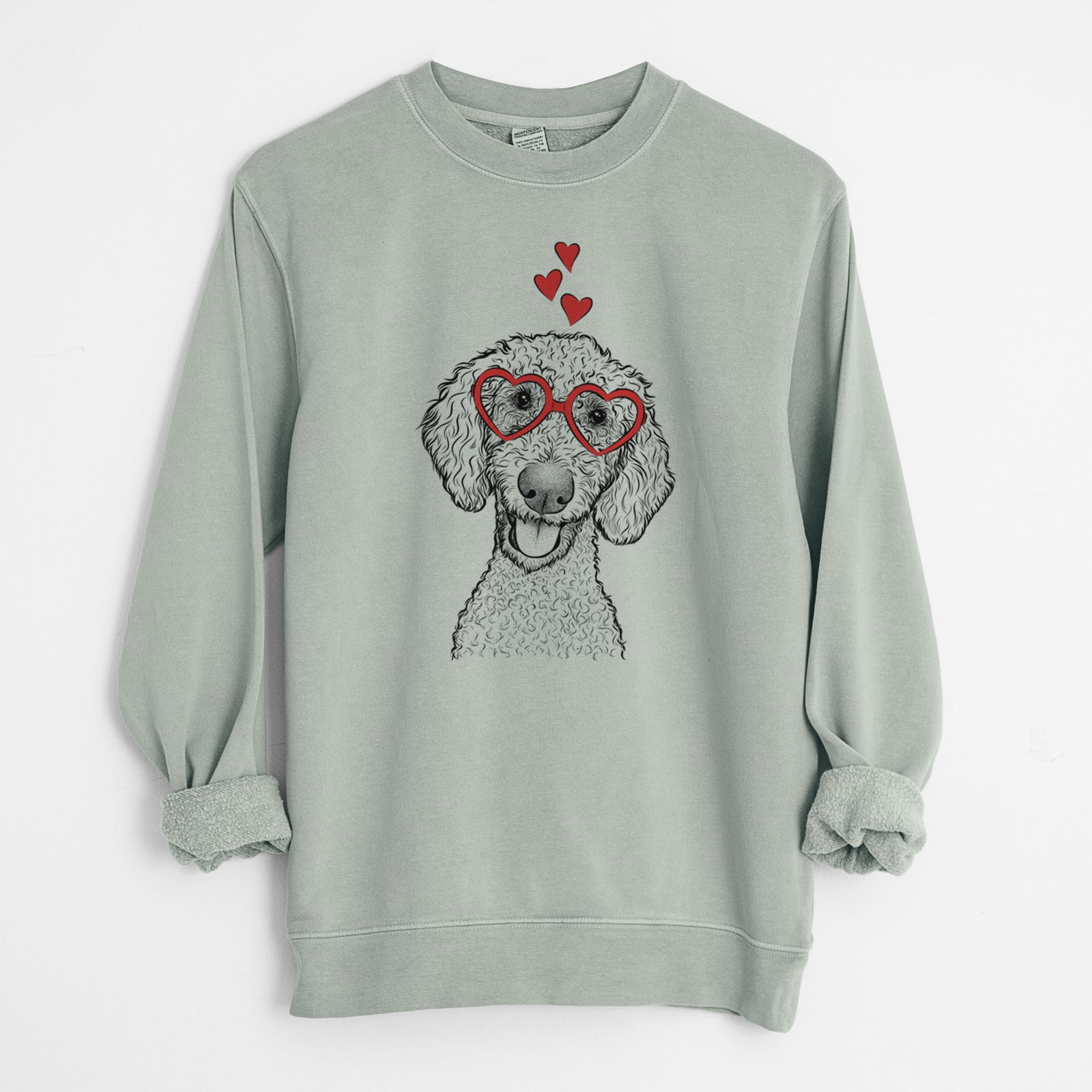 Hand-drawn sketch of Fenway the Goldendoodle wearing heart-shaped glasses on a Sage Unisex pigment dyed crew sweatshirt