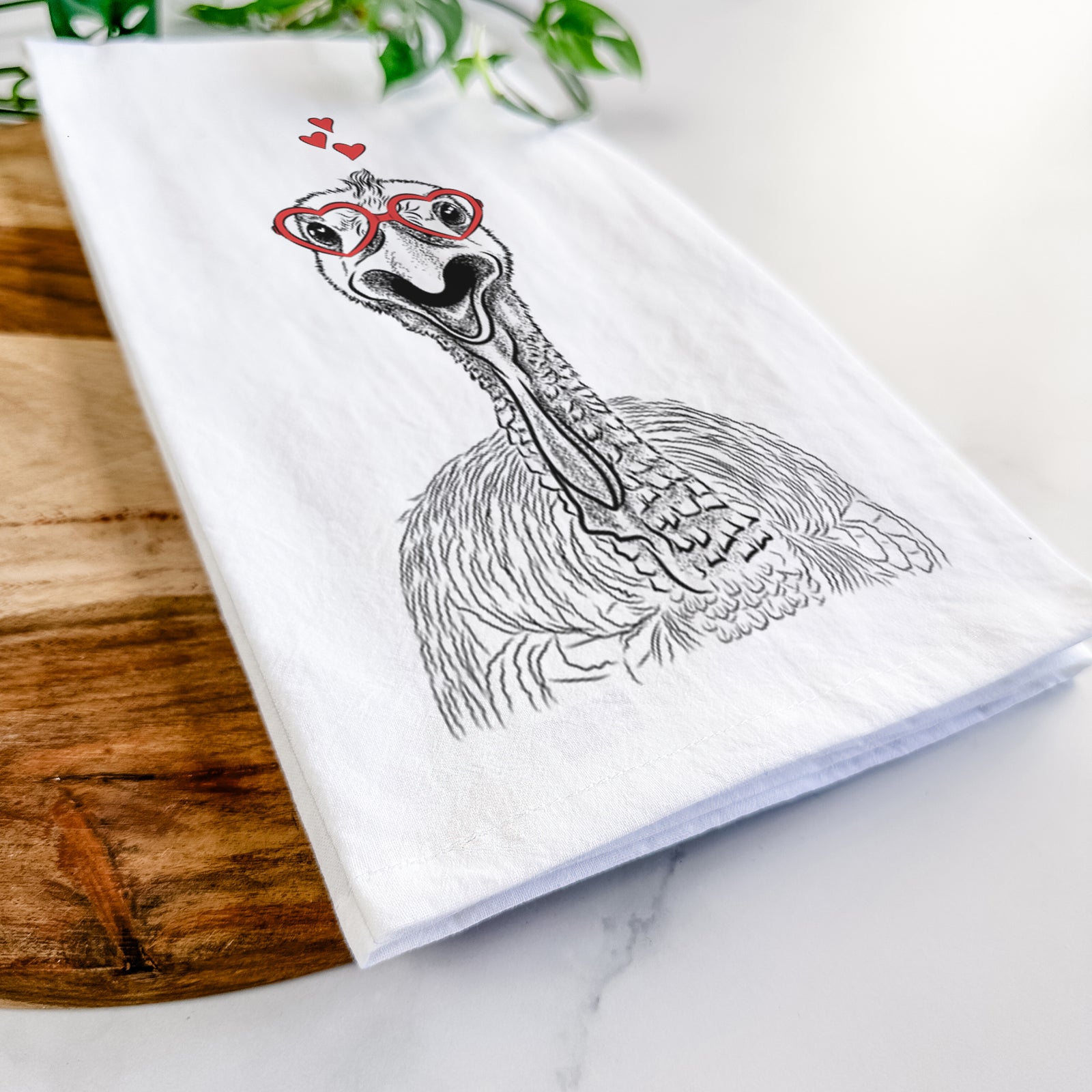 Hand-drawn sketch of Gobble the Turkey wearing heart-shaped glasses on a tea towel