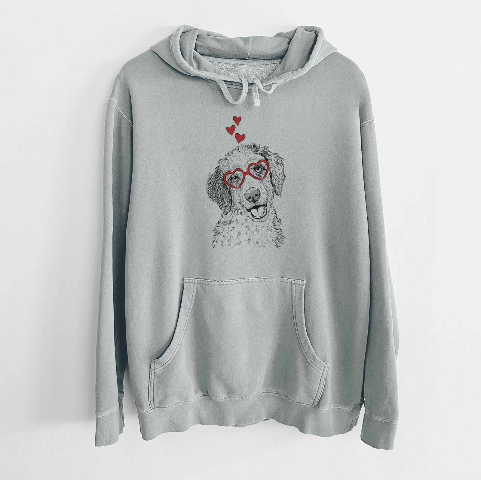 Hand-drawn sketch of Hoge the Aussiedoodle wearing heart-shaped glasses on a Sage Unisex pigment dyed hoodie