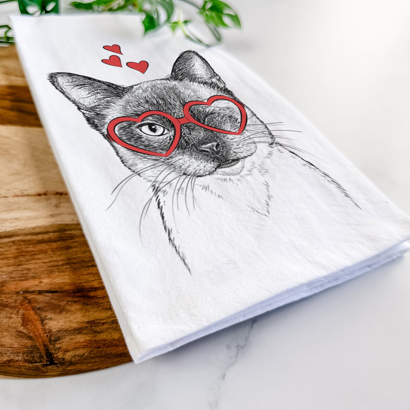 Hand-drawn sketch of Hoggle the Siamese Cat wearing heart-shaped glasses on a tea towel