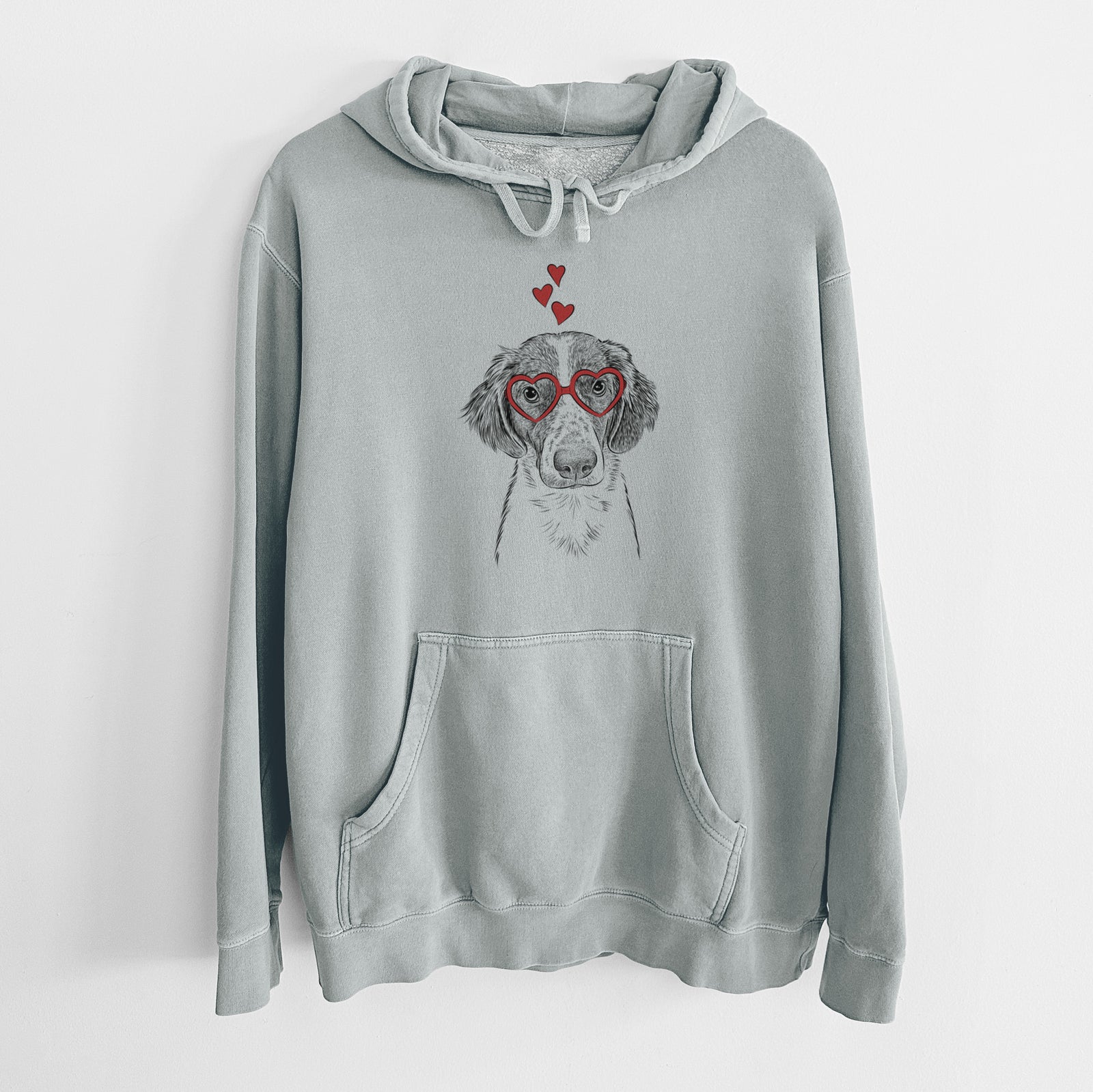 Hand-drawn sketch of Holly the Brittany Spaniel wearing heart-shaped glasses on a Sage Unisex pigment dyed hoodie
