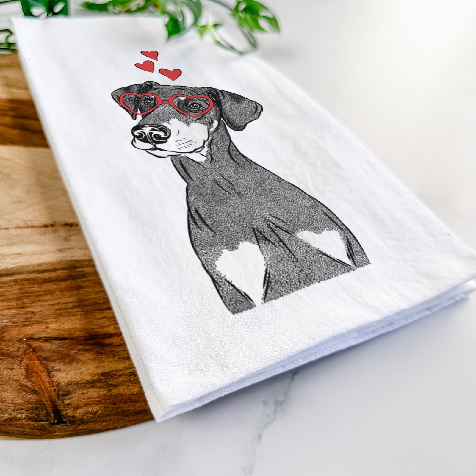 Hand-drawn sketch of Iroh the Doberman Pinscher wearing heart-shaped glasses on a tea towel