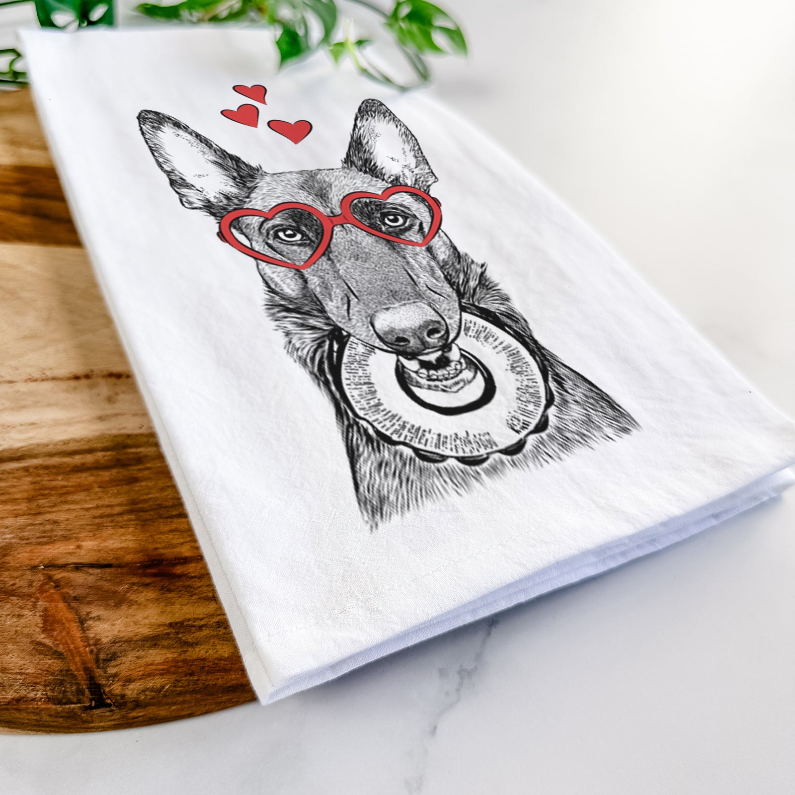 Hand-drawn sketch of Juno the Belgian Malinois wearing heart-shaped glasses on a tea towel