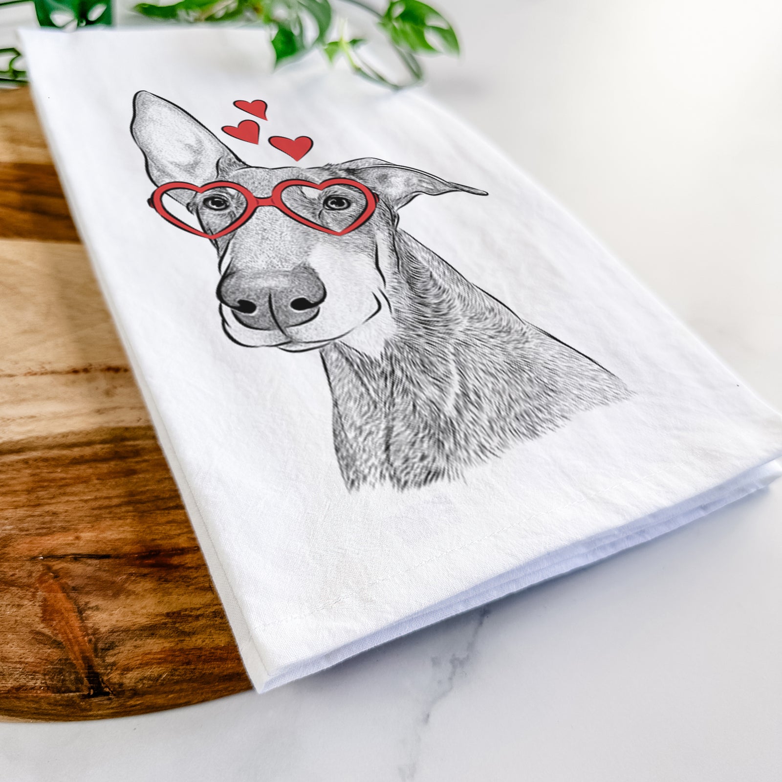 Hand-drawn sketch of Kain the Doberman Pinscher wearing heart-shaped glasses on a tea towel